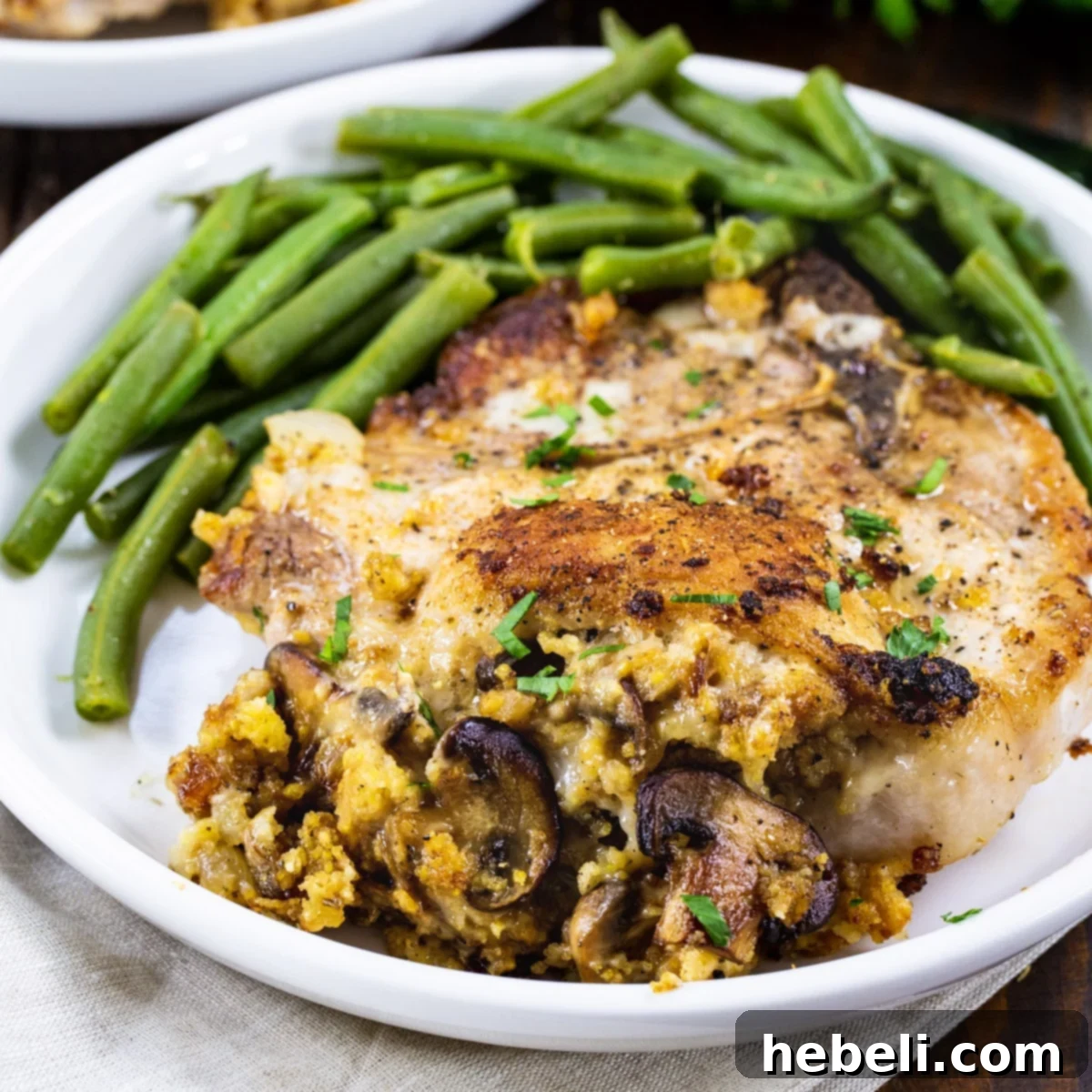 Delicious Cornbread Stuffed Pork Chops on a plate with fresh green beans and mashed potatoes, ready to be served.