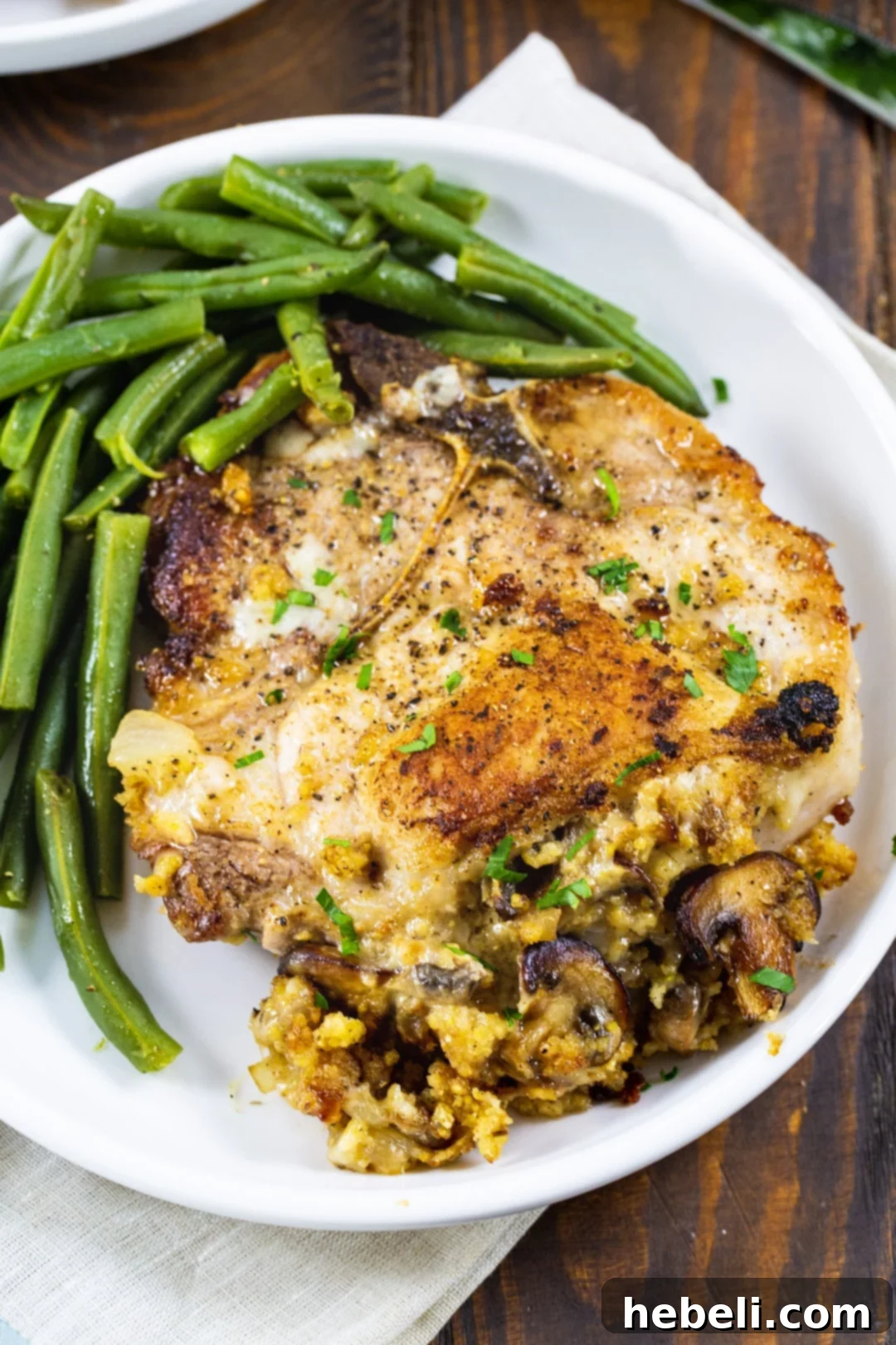 Overhead view of a perfectly stuffed pork chop on a plate, showcasing the golden-brown crust and visible stuffing.