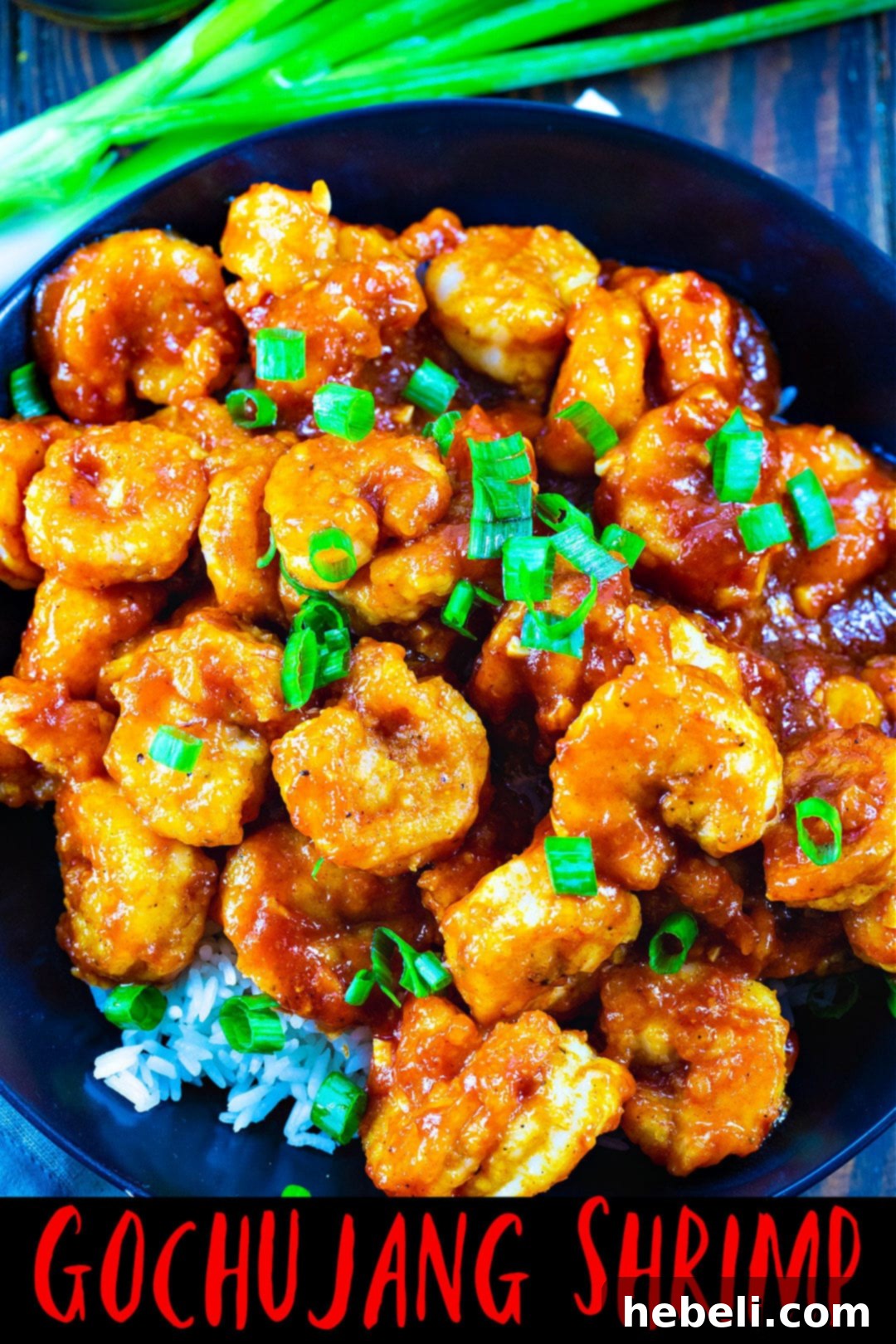 Overhead view of Gochujang Shrimp arranged beautifully over white rice in a sleek black bowl.