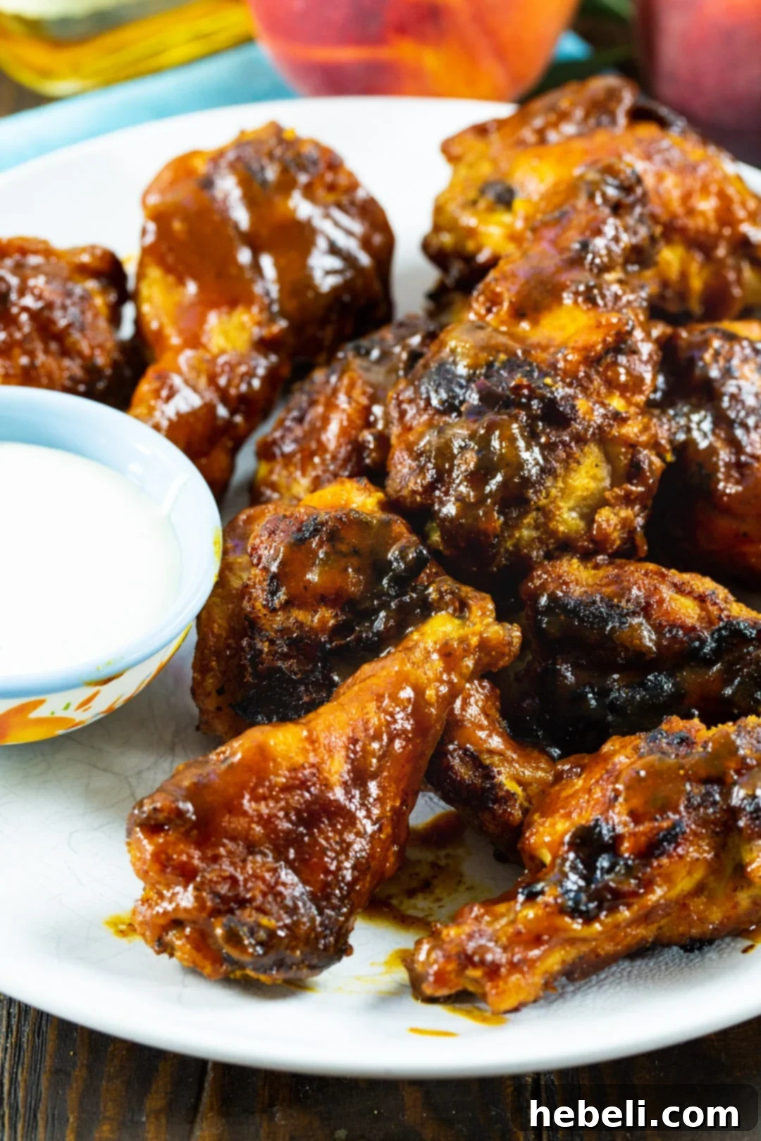 Oven-baked chicken wings coated in a glistening Bourbon Peach BBQ sauce, garnished with fresh herbs.