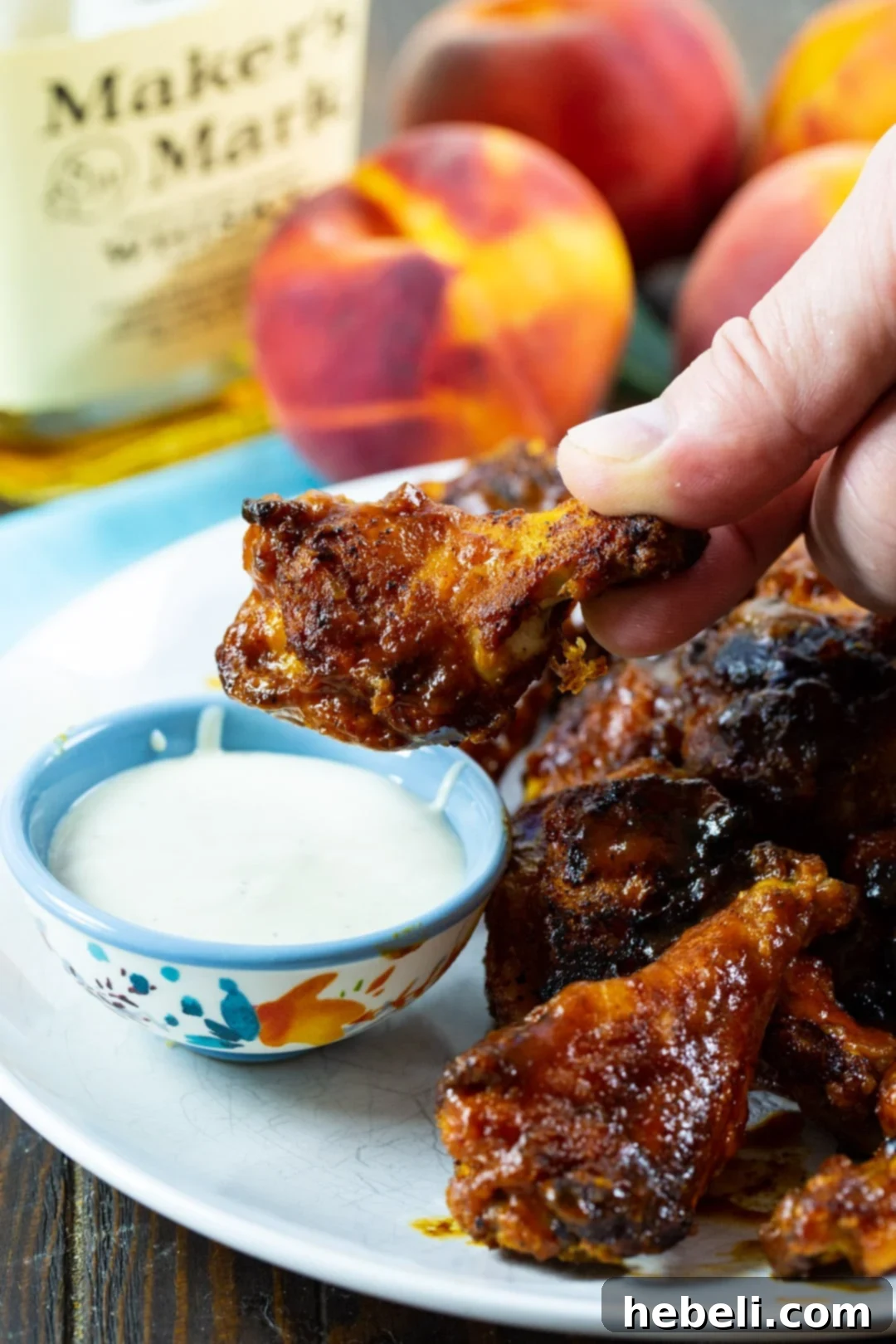 A crispy Bourbon Peach BBQ Wing being dipped into a bowl of creamy Ranch dressing.