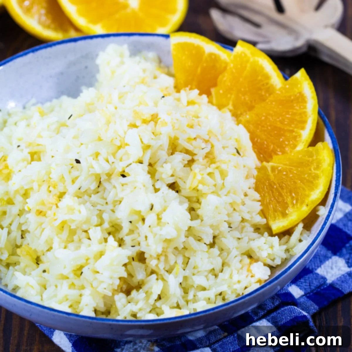 Vibrant Orange Rice in a blue bowl with fresh orange segments artfully arranged around the edges, highlighting its citrusy appeal.