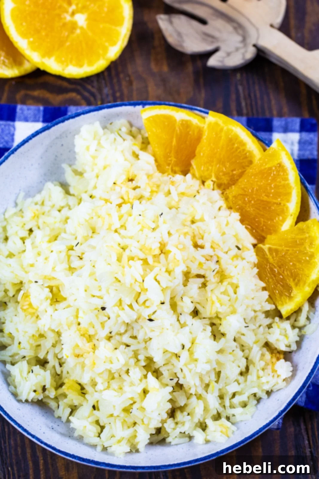 Close-up of fluffy Orange Rice in a white bowl, accompanied by fresh orange slices, showcasing its inviting texture and citrus appeal.