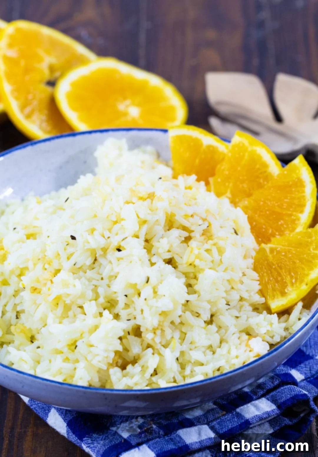 Close-up of fluffy Orange Rice in a blue bowl, garnished with fresh orange segments, illustrating its appetizing texture and vibrant color.