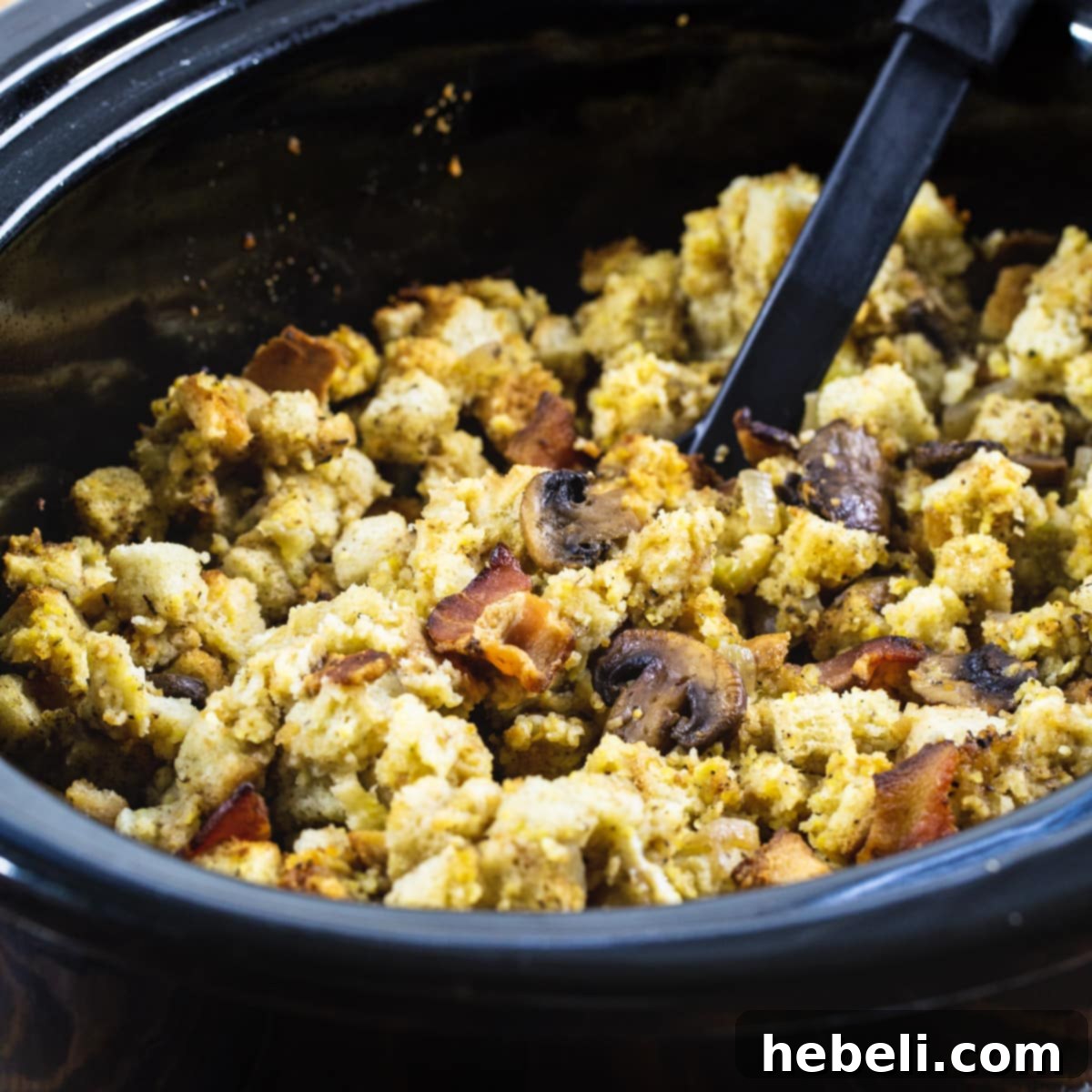Savory Slow Cooker Bacon Mushroom Dressing 2 Slow Cooker Bacon Mushroom Dressing in a black slow cooker, ready to serve.