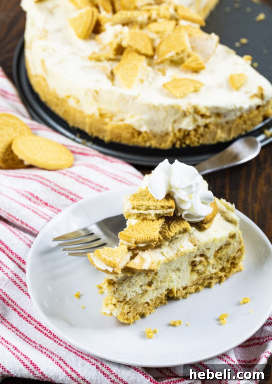 A whole No-Bake Golden Oreo Cheesecake with a slice removed, showing its rich texture and golden crust, ready to be served.