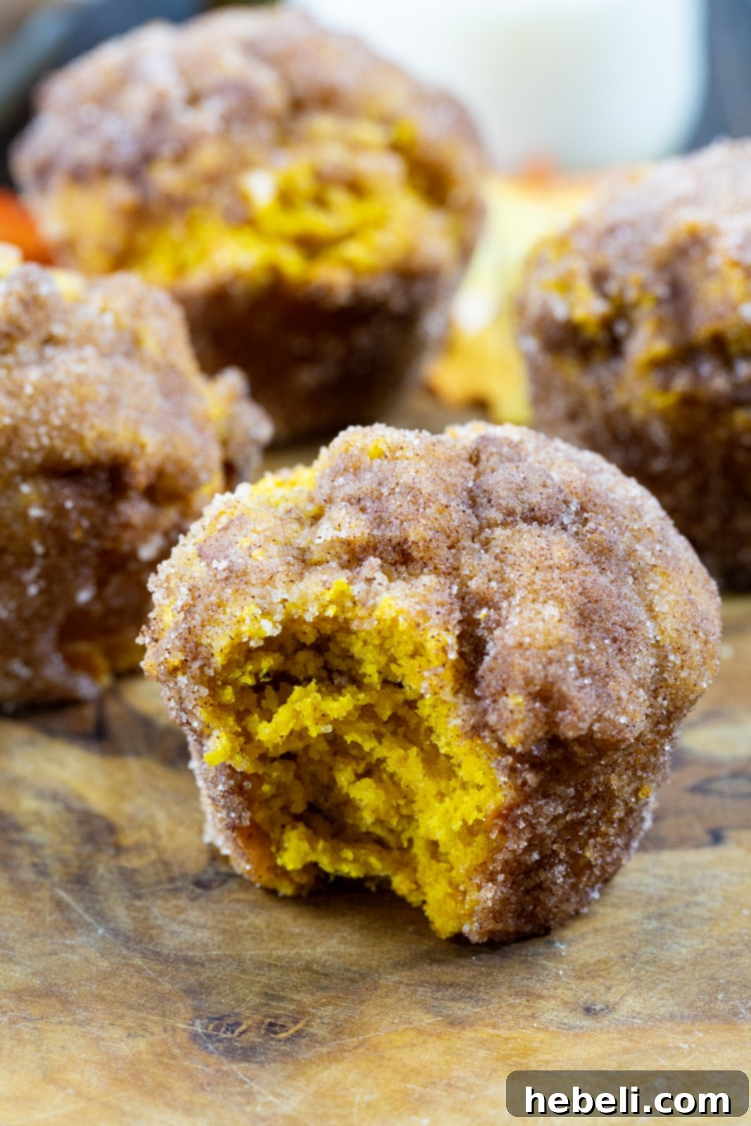 An assortment of Pumpkin Doughnut Muffins displayed on a rustic wooden serving board, ready to be enjoyed.