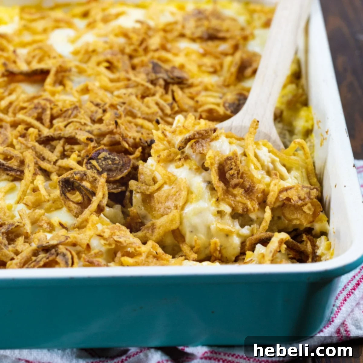 Spoon scooping up a generous portion of French Onion Chicken and Rice Casserole, showcasing its creamy texture and golden topping.