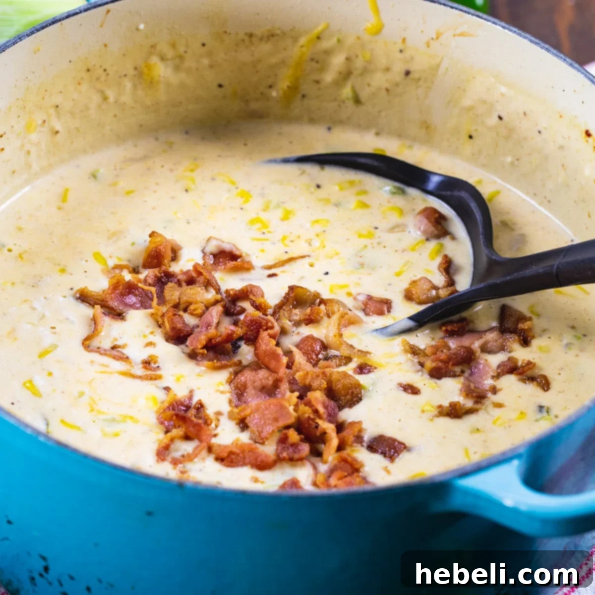 Rich and creamy Jalapeno Popper Corn Chowder in a blue Dutch oven, garnished with crumbled bacon.