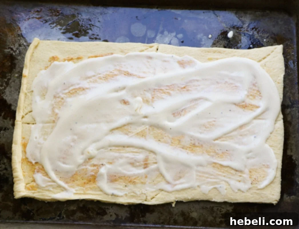 Alfredo sauce spread on crescent dough.