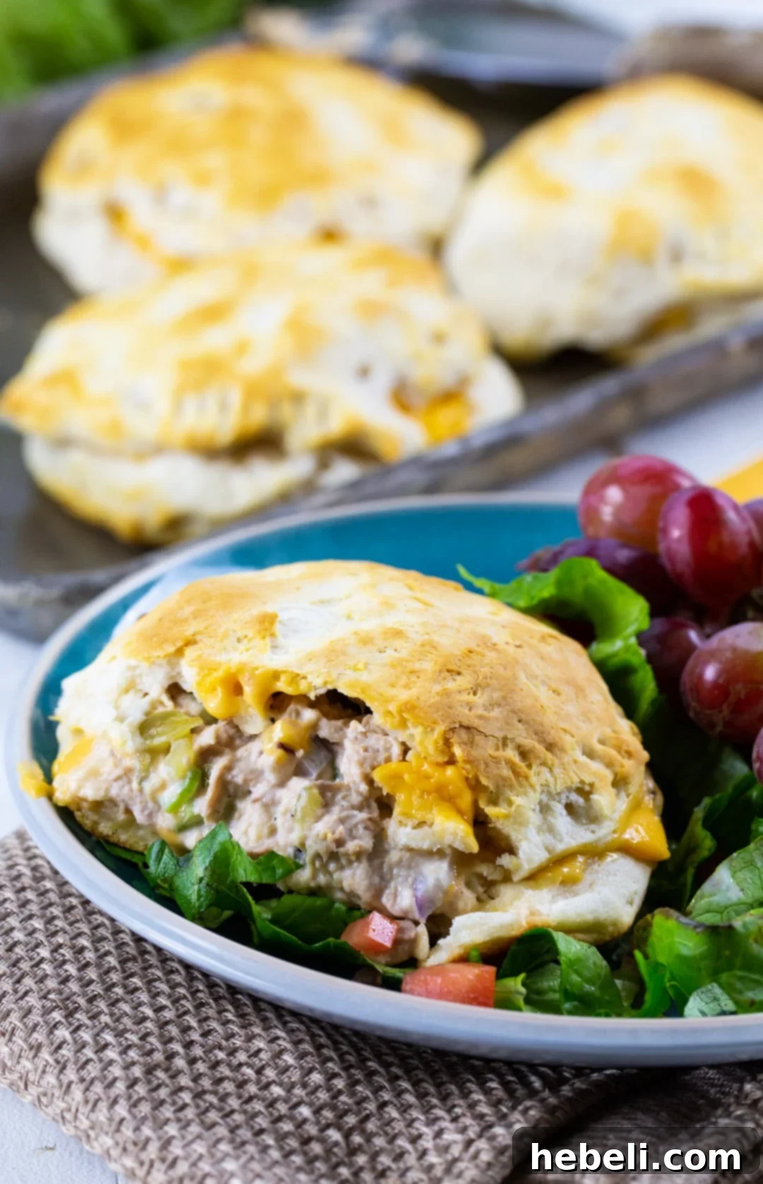 A baked Biscuit Tuna Melt on a plate with red grapes.