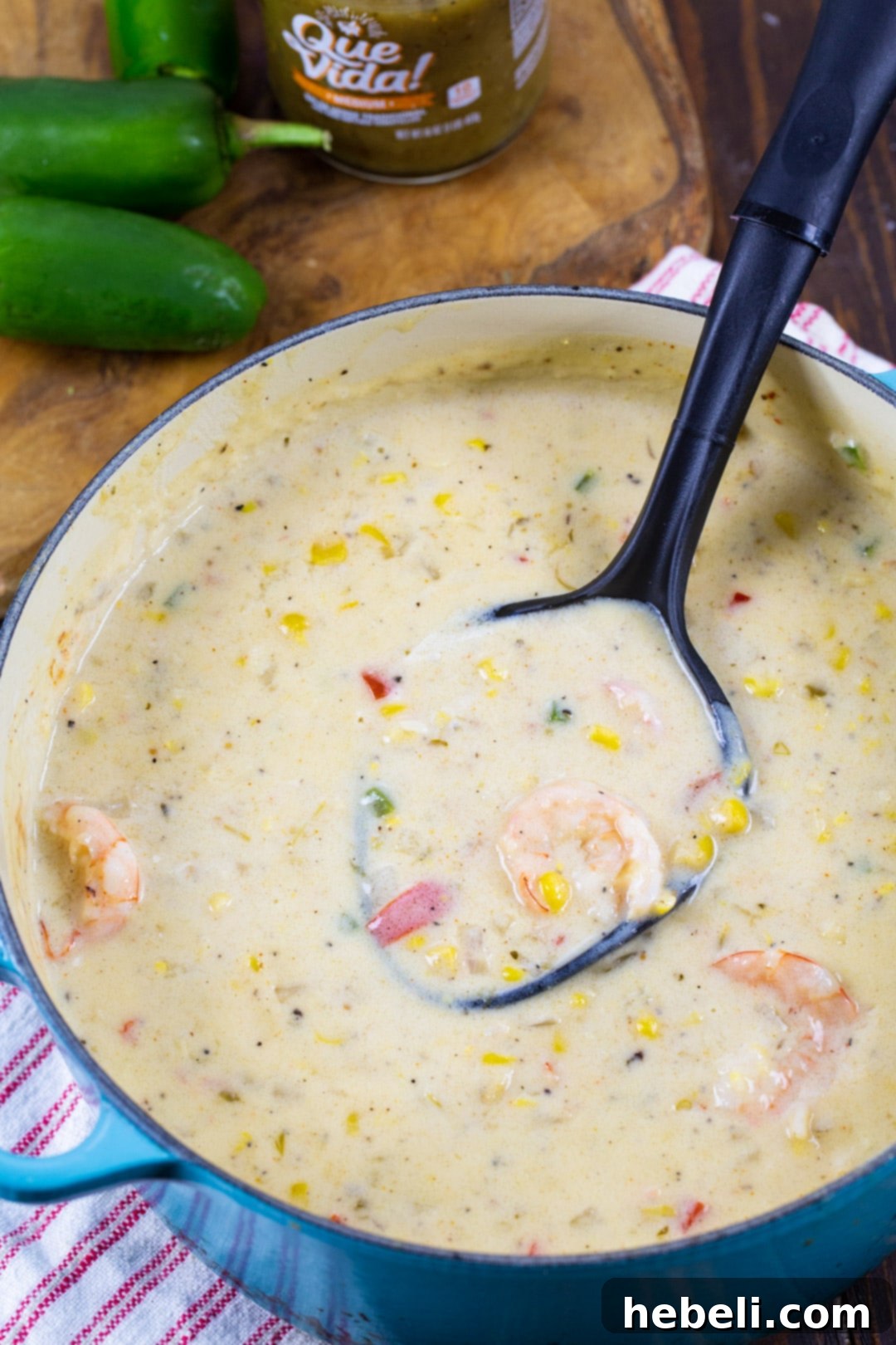 Close-up of creamy Southwestern Shrimp Chowder in a blue Dutch oven, showcasing plump shrimp, kernels of corn, and diced jalapeños, ready for serving.