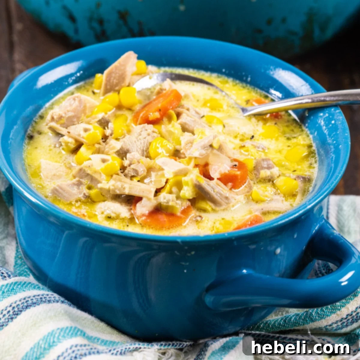 A steaming bowl of creamy Turkey Corn Chowder, garnished with fresh herbs, served in a rustic blue bowl.