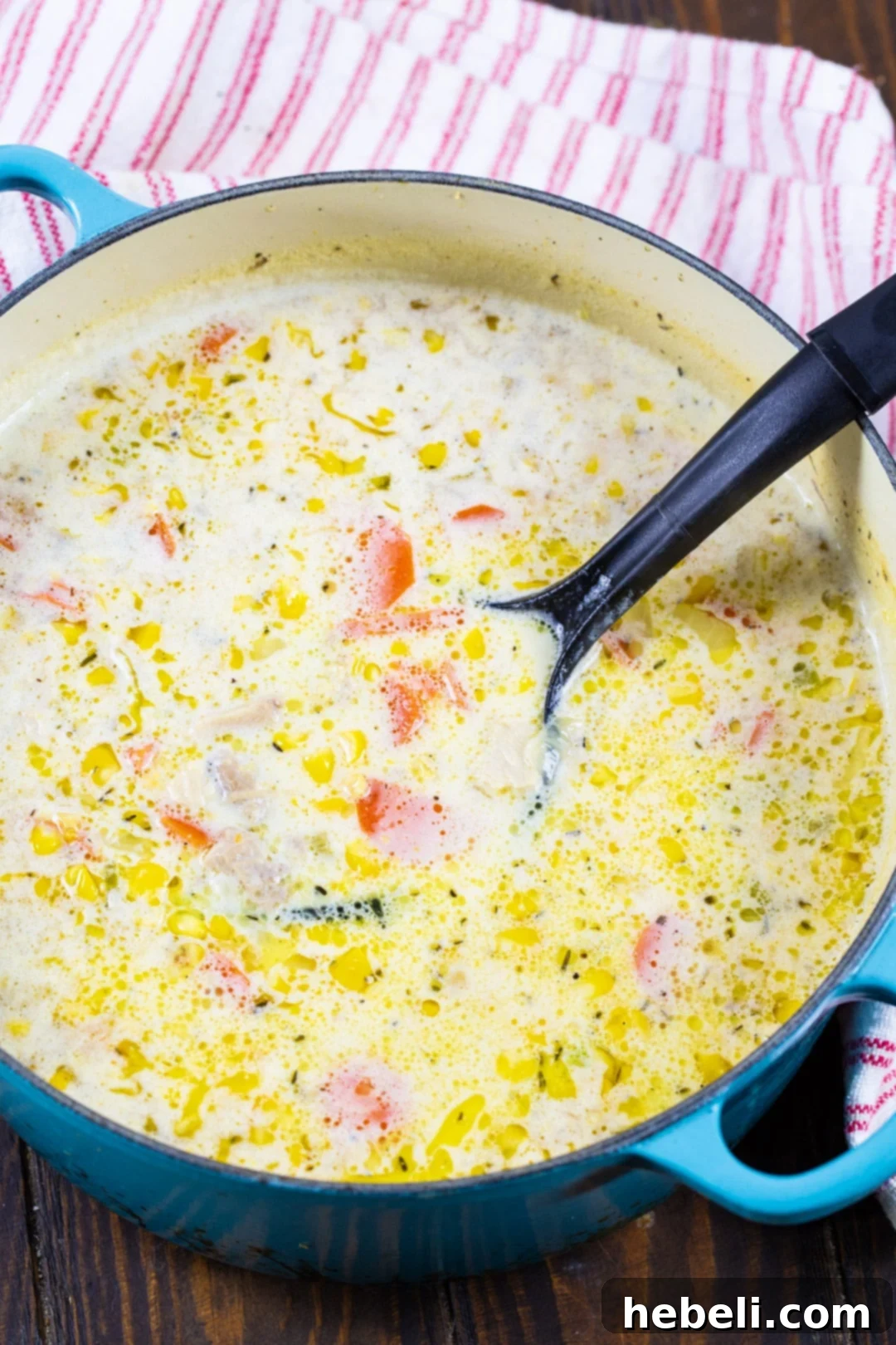 Turkey Corn Chowder simmering in a large, vibrant blue Dutch oven on a stovetop.