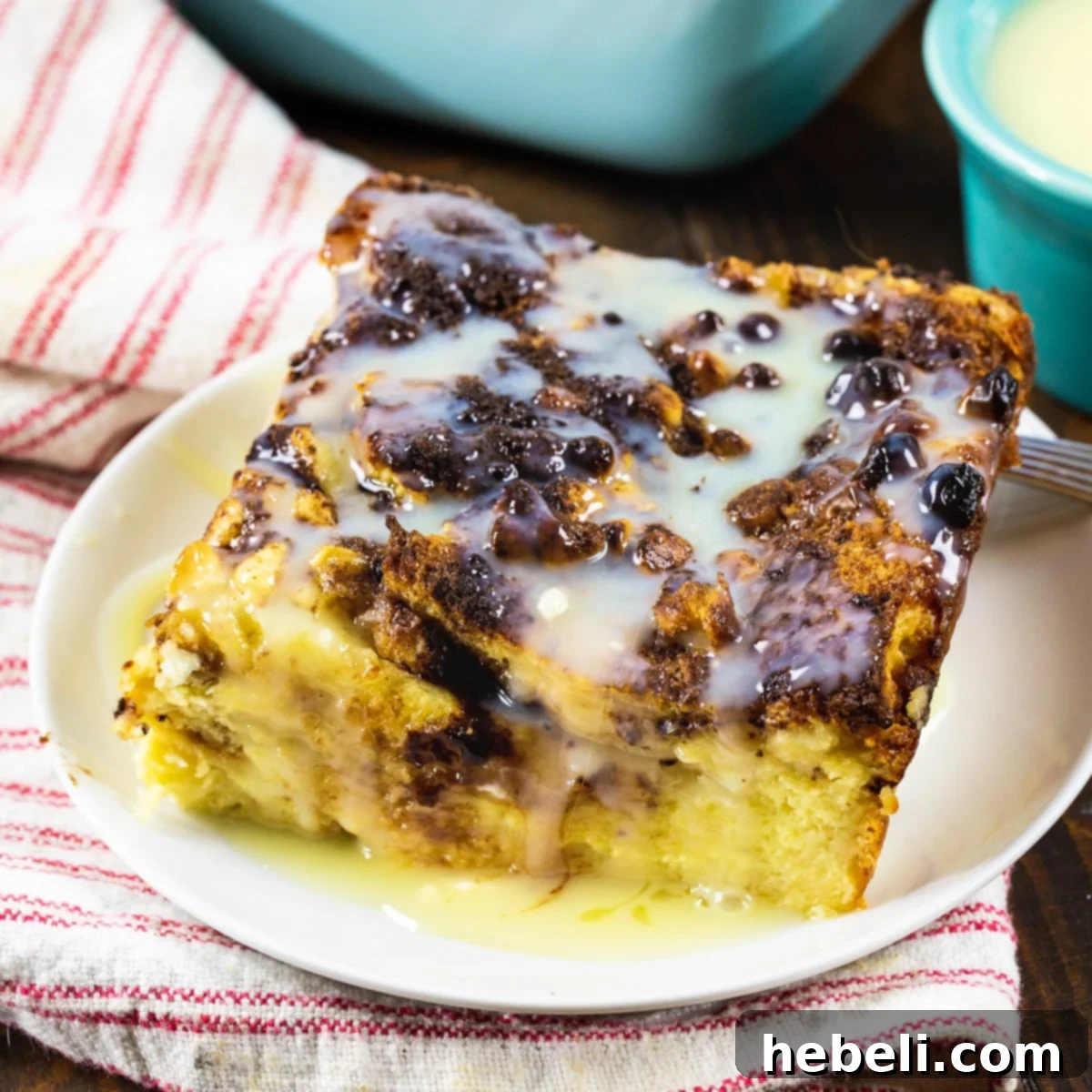 A beautiful slice of White Chocolate Bread Pudding on a white plate, showcasing its golden crust and creamy interior.