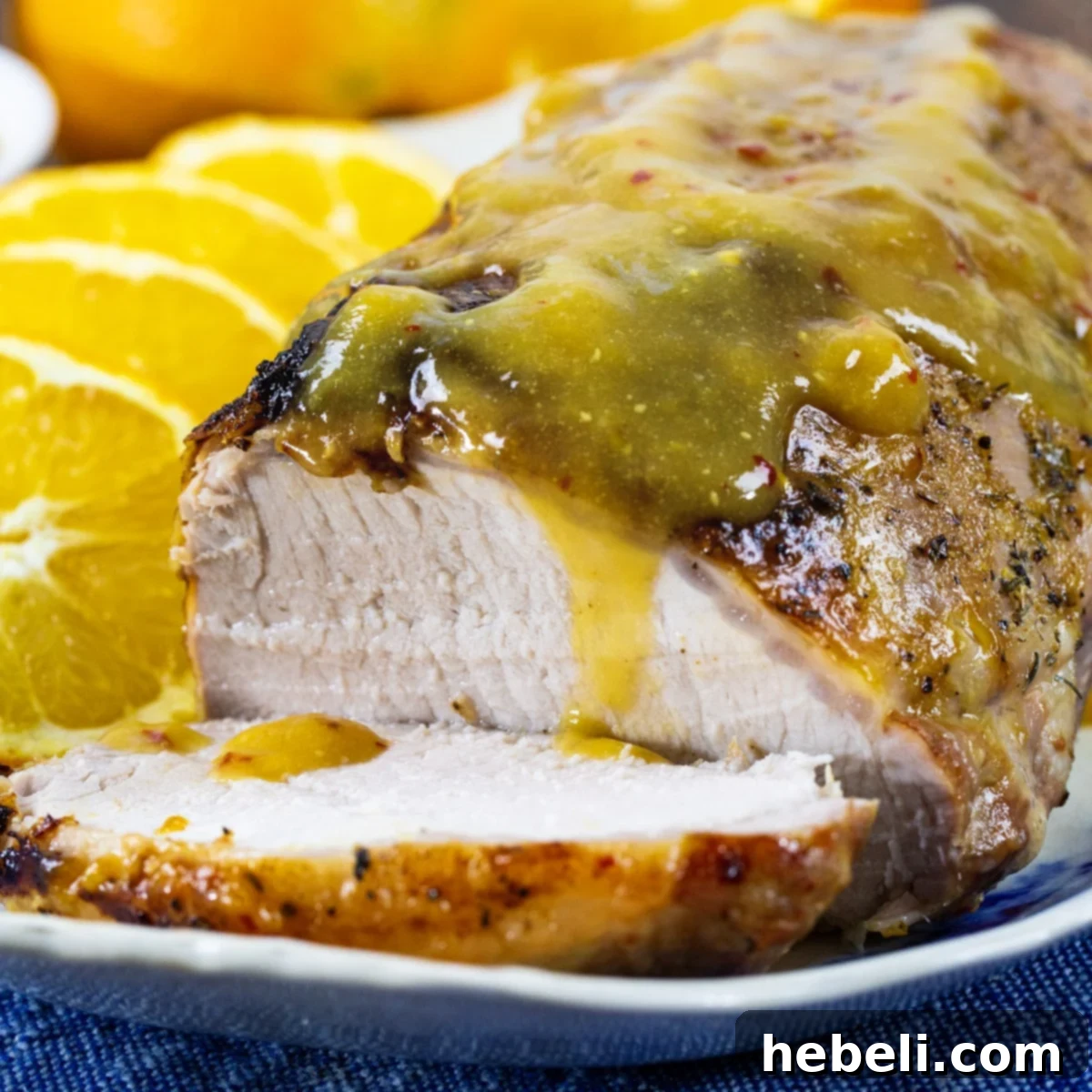 Orange-Glazed Pork Loin on a serving platter with fresh orange slices, ready to be served for a festive meal.
