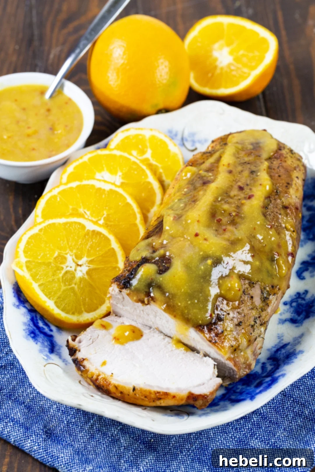 Close-up of Orange-Glazed Pork Loin, showing the rich, caramelized glaze and perfectly cooked meat, garnished with fresh orange slices.