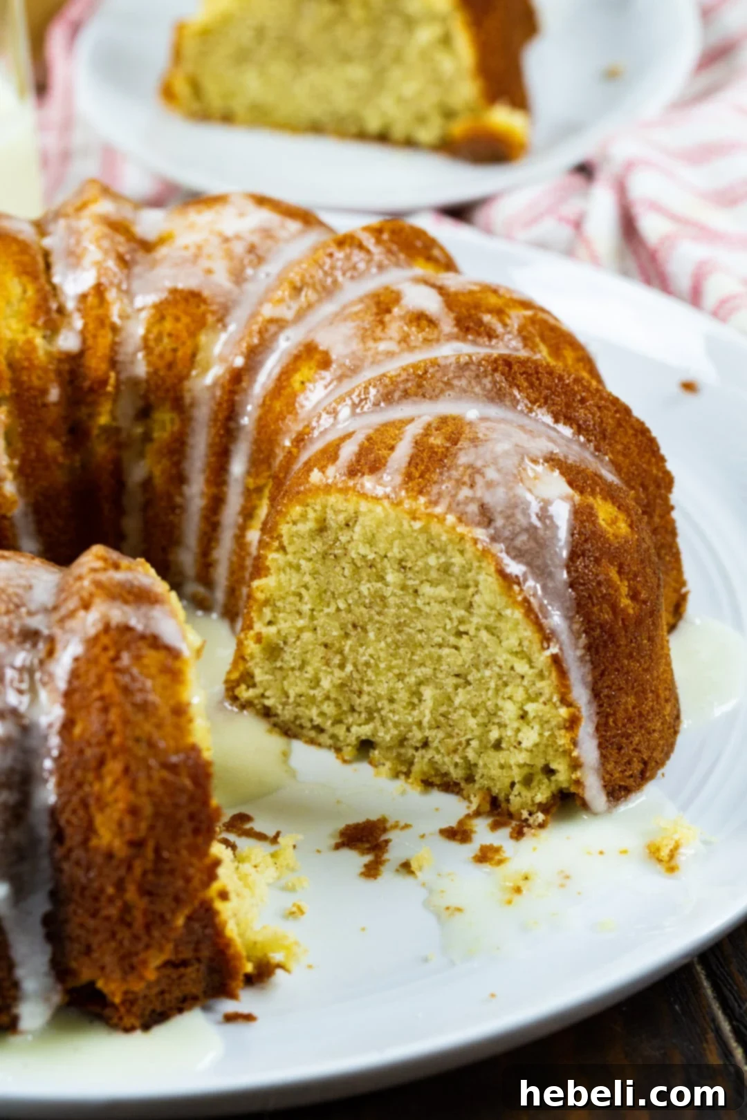 Holiday Eggnog Pound Cake 3 A whole Eggnog Pound Cake with a slice gracefully removed, beautifully adorned with a generous eggnog glaze, perfectly ready for serving at a festive gathering.