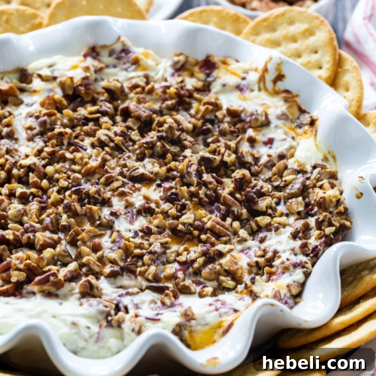 Hot Pecan Beef Dip surrounded by a variety of crackers on a serving tray.