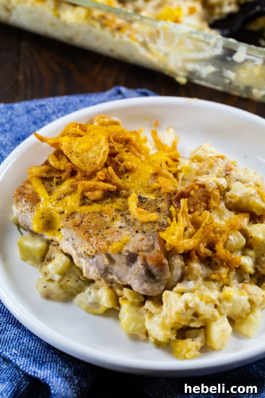 A serving of Pork Chop Potato Casserole on a white plate, showing the creamy potatoes and tender pork.