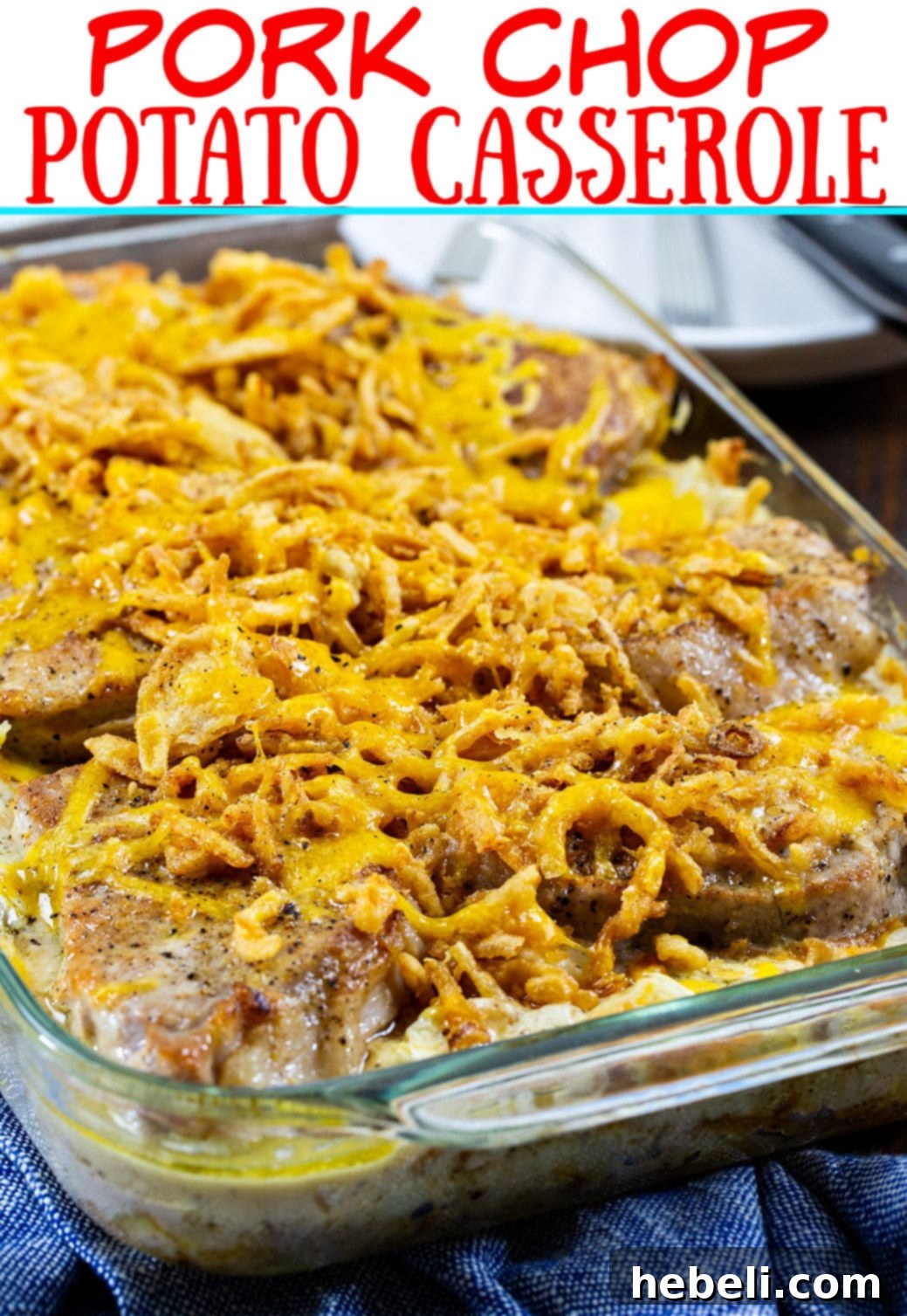 Close-up of a rustic styled serving of Pork Chop Potato Casserole in a casserole dish, with a wooden spoon.