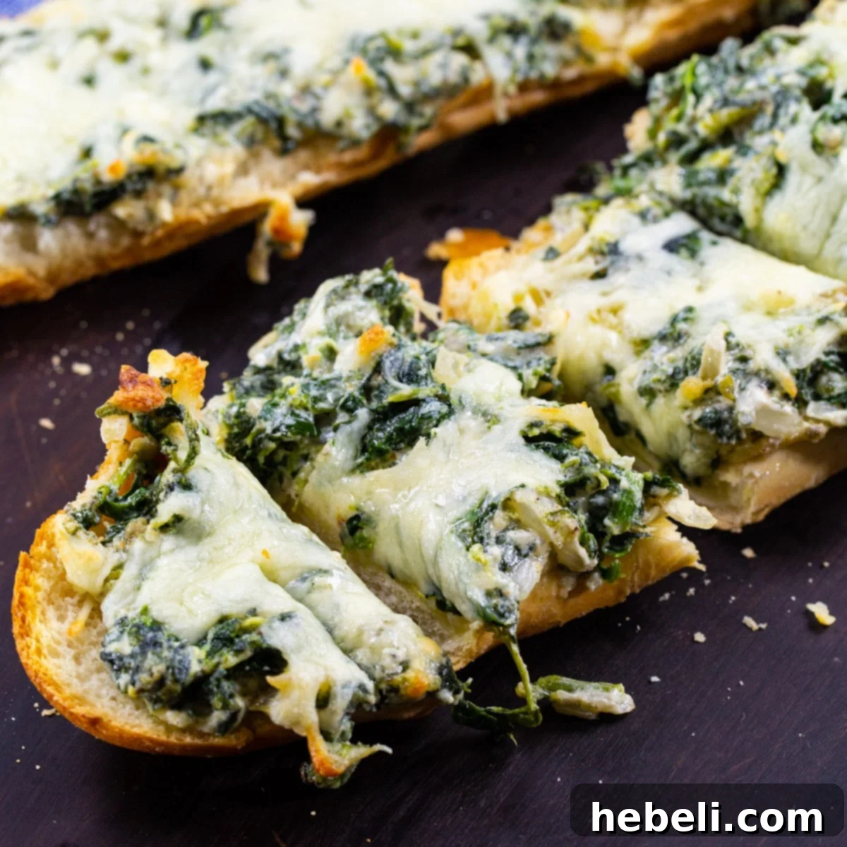 Savory Spinach Loaf 2 Spinach Bread cut into slices, showing the cheesy, garlicky spinach topping.