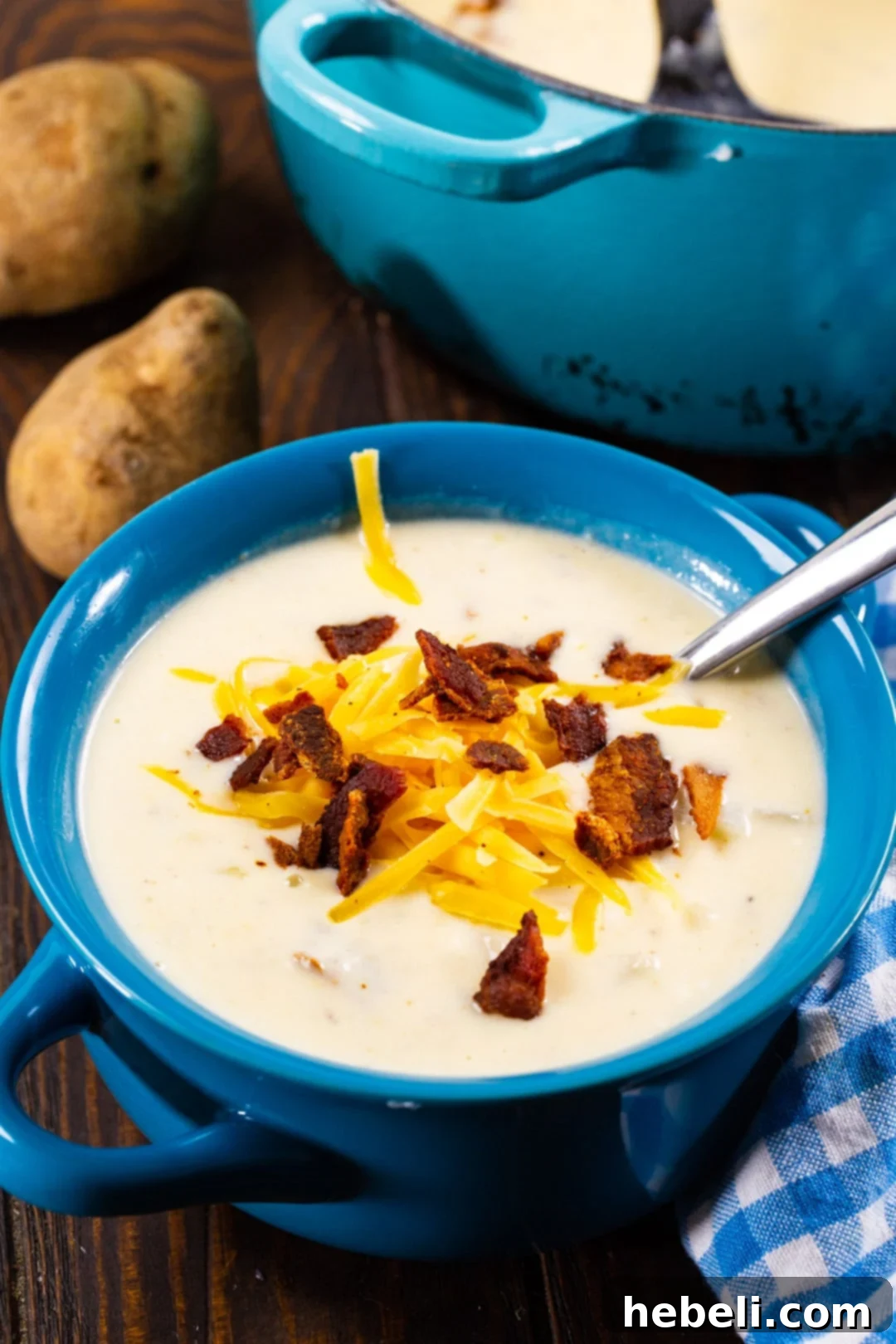 Loaded Bacon Potato Soup 4 A close-up of Easy Bacon and Potato Soup in a serving bowl, generously topped with shredded cheddar cheese, crispy bacon bits, and vibrant green onions, emphasizing its inviting texture.