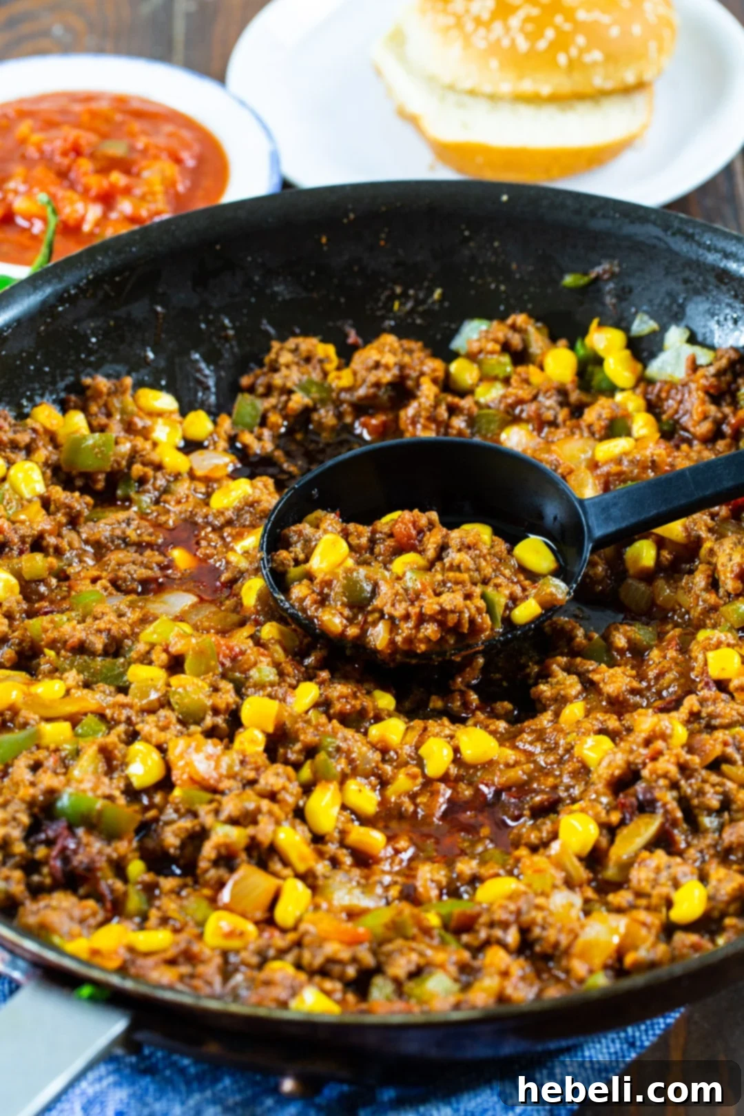 Tex-Mex Sloppy Joes mixture simmering in a large skillet with bell peppers, onions, and spices.