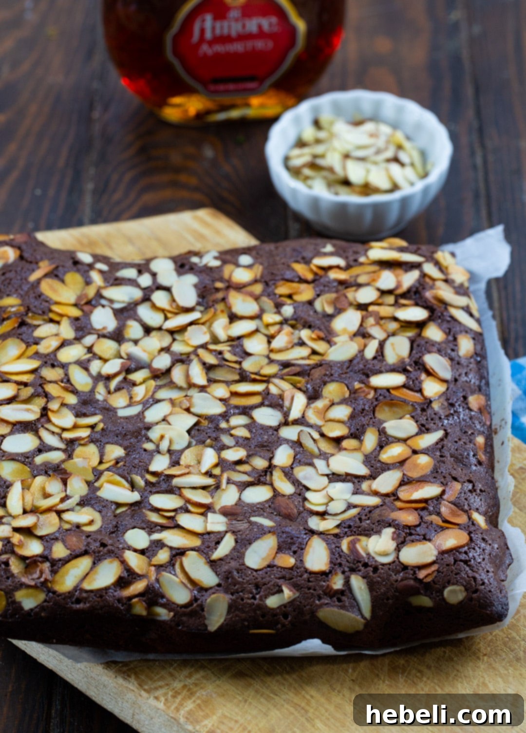 Decadent Amaretto Fudge Brownies 3 Amaretto Brownies arranged artfully on a rustic wooden cutting board.