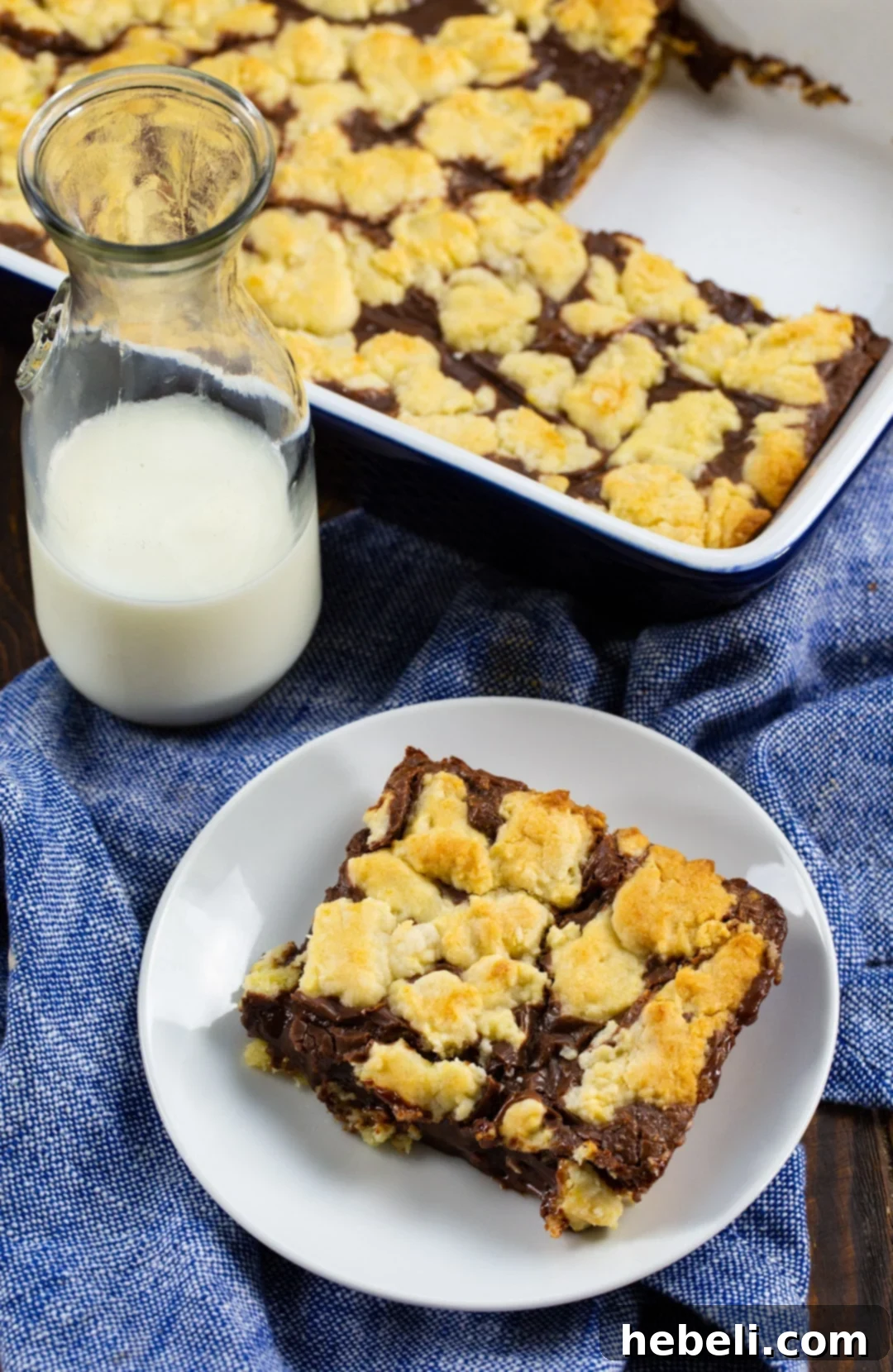 Cake Mix Bar on plate, glass of milk, and bars in baking dish, creating a delicious scene.