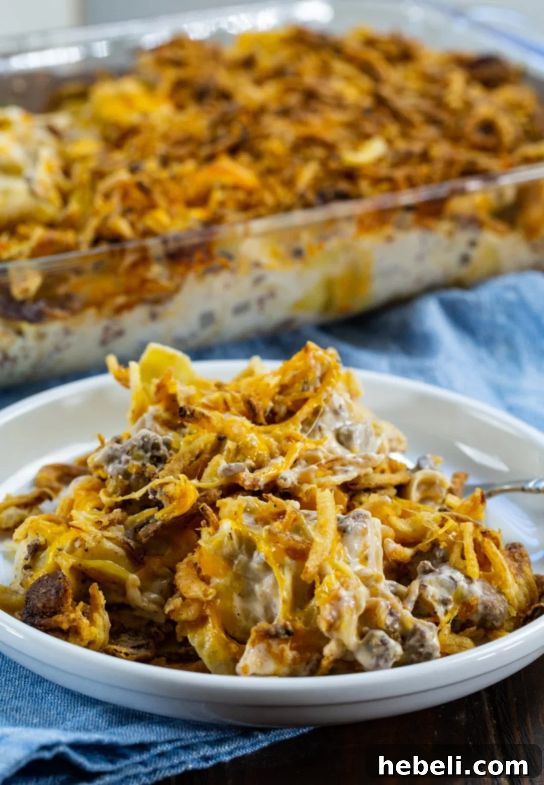 A single serving of French Onion Ground Beef Casserole on a white plate, showcasing the creamy noodles, beef, and crispy onion topping.