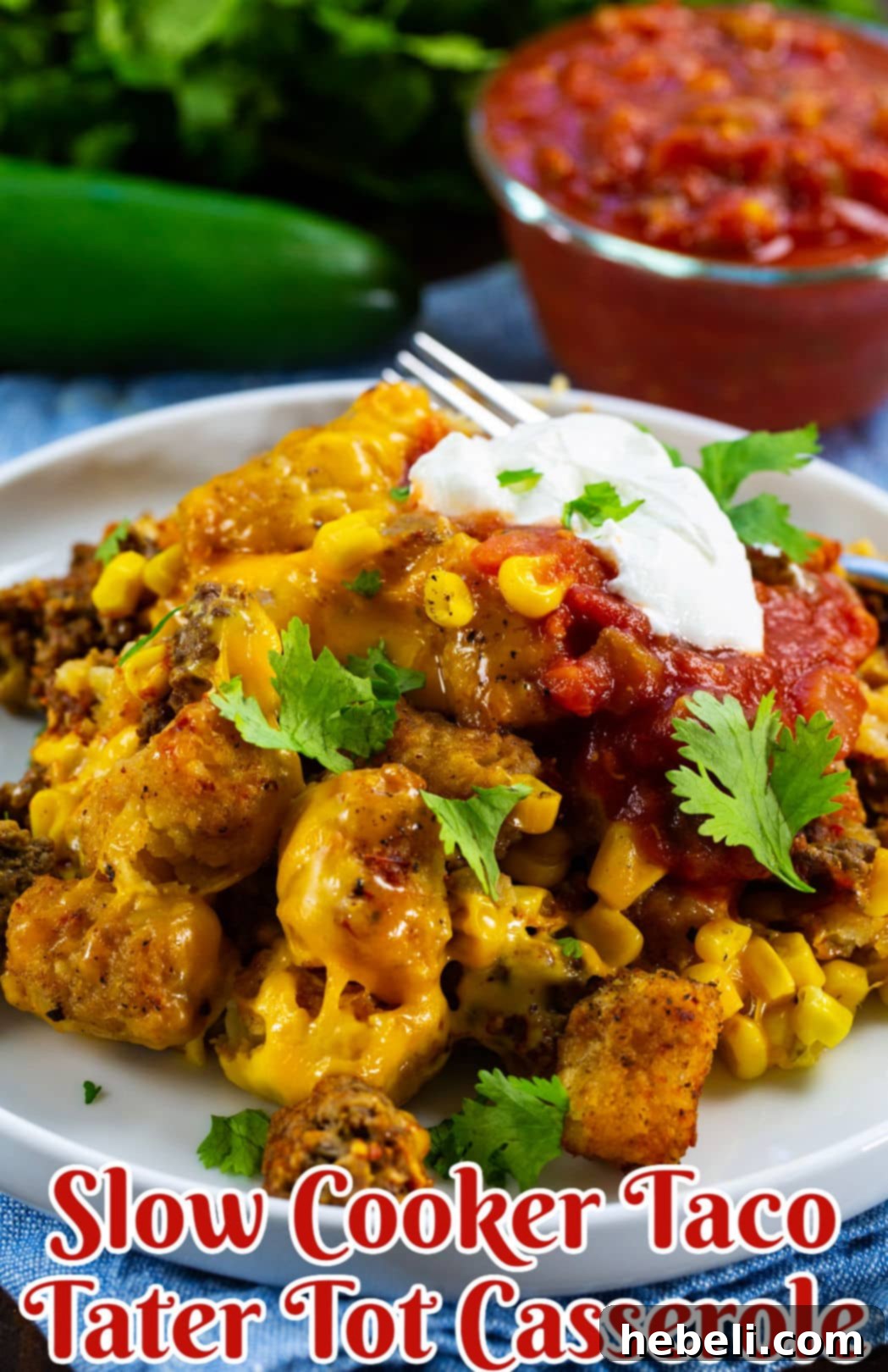 Slow Cooker Taco Tater Tot Casserole dished up on a plate with sour cream and cilantro.