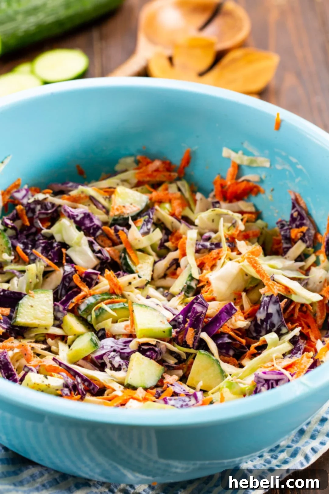 Cucumber Coleslaw being mixed in a large blue bowl.