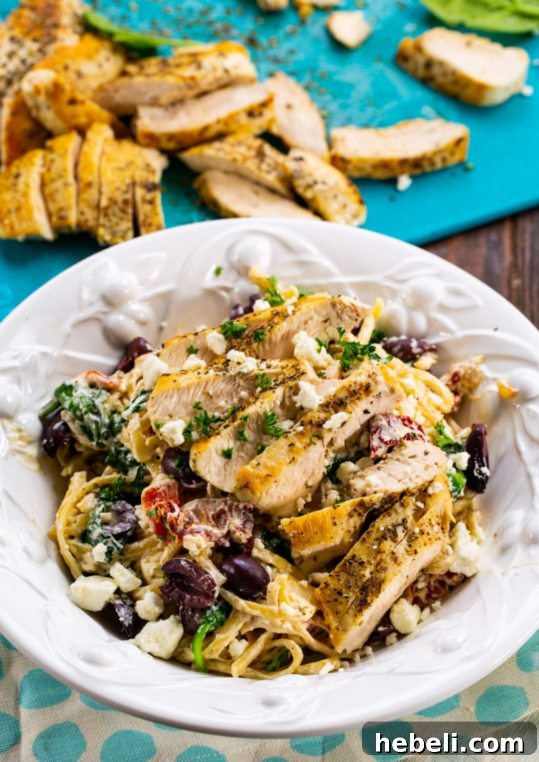 Zesty Greek Chicken Pasta 3 Greek Pasta with sliced chicken in background.