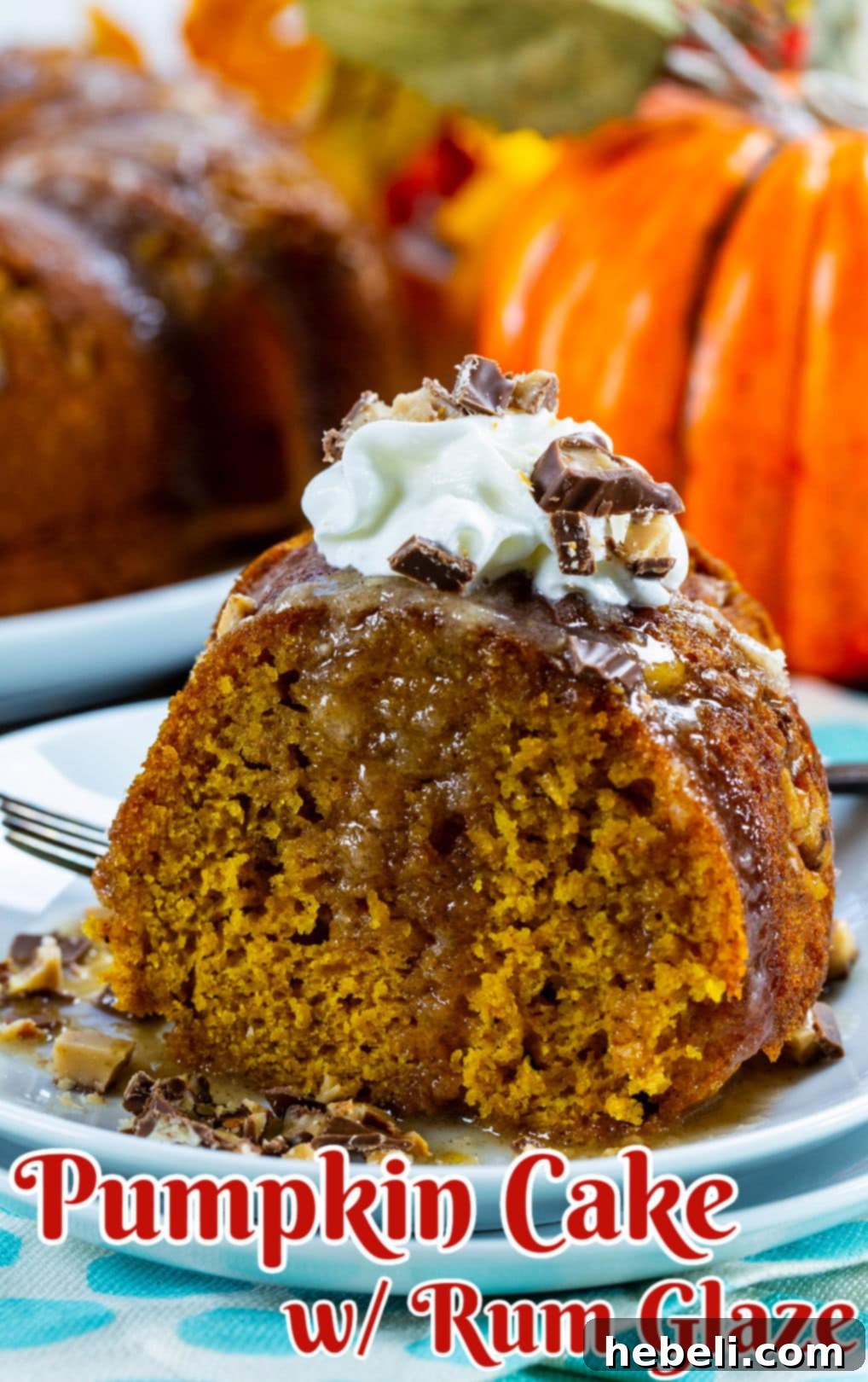 A close-up shot of a single slice of moist Pumpkin Cake with Rum Glaze, garnished with a sprinkle of crushed Heath bar.