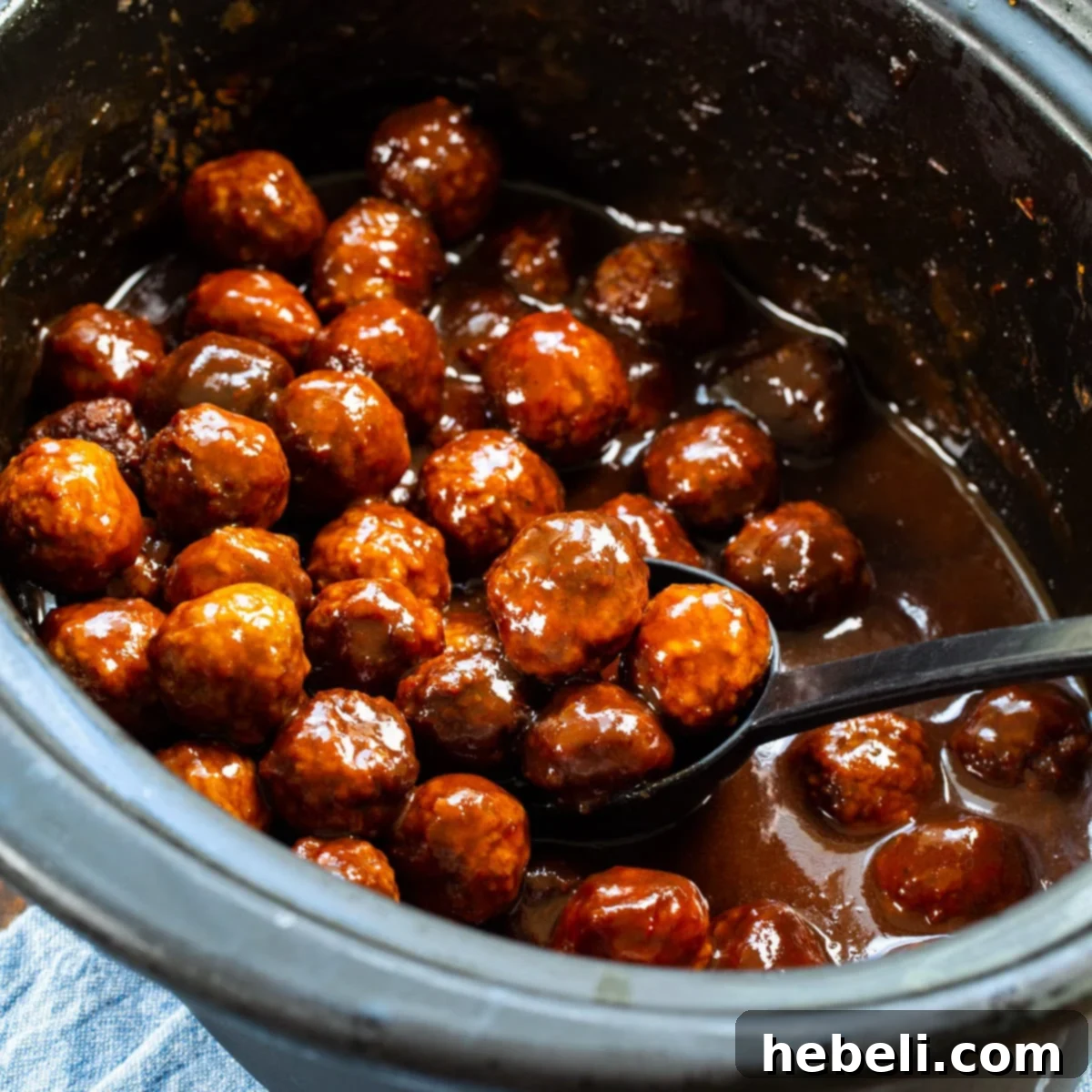 Sweet and Spicy Grape Meatballs 2 Close-up of Spicy Grape Meatballs in a slow cooker, showcasing their glossy, rich sauce.