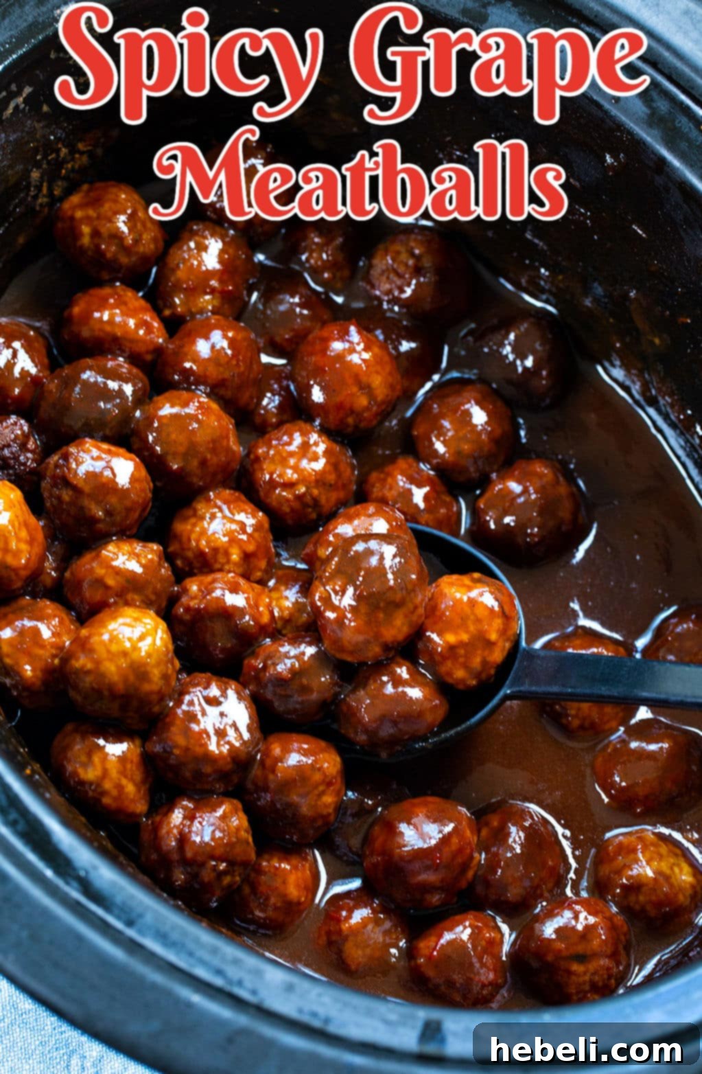 Sweet and Spicy Grape Meatballs 3 Spicy Grape Meatballs simmering in a crock pot, coated in a thick, dark sauce.