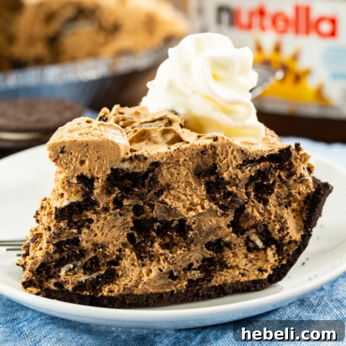 A perfect slice of Nutella Oreo Pie on a white plate, showcasing its creamy layers and cookie chunks.