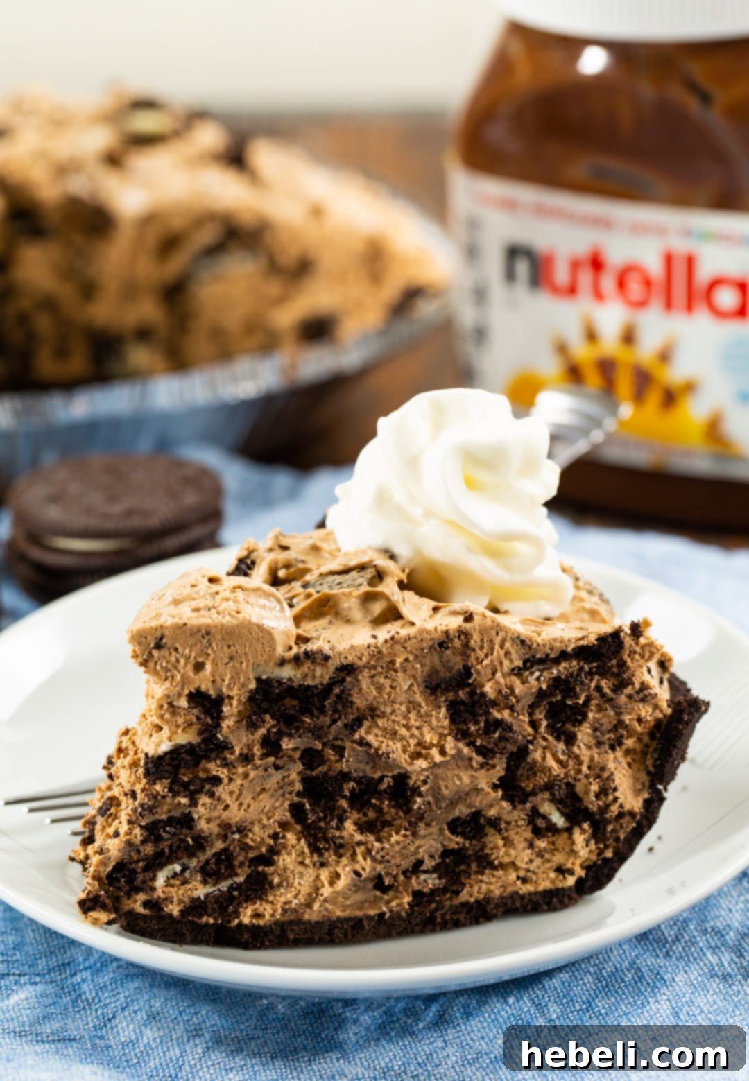 Close-up of a slice of Nutella Oreo Pie, perfectly topped with a dollop of whipped cream.