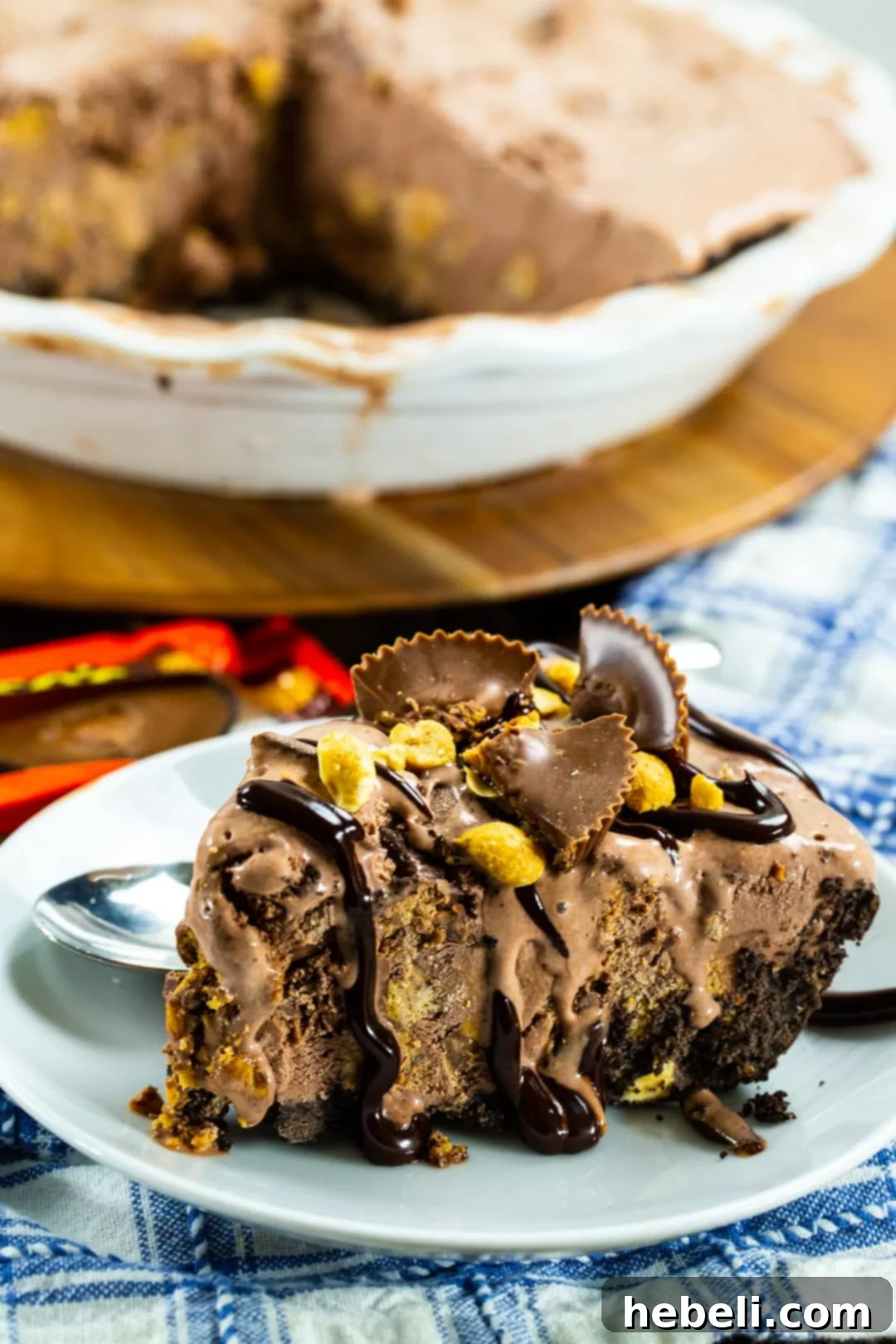 A close-up shot of a Chocolate Peanut Butter Ice Cream Pie with the top visible, showing the creamy chocolate ice cream studded with chunks of peanut butter cups and the dark Oreo crust edge.