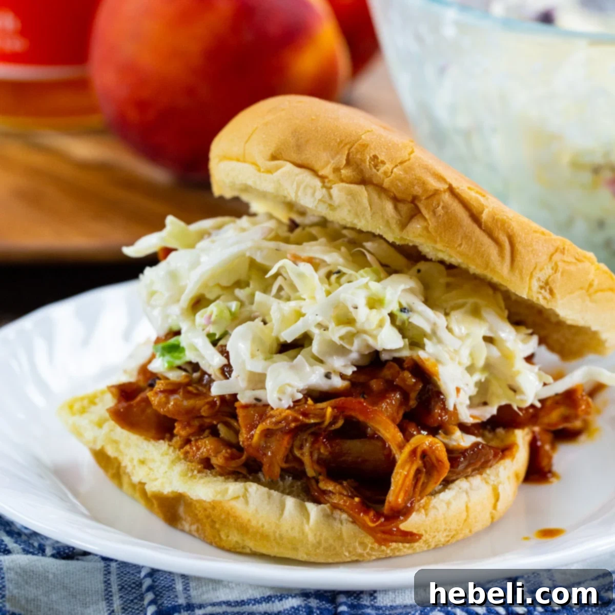 Slow Cooked BBQ Peach Pulled Chicken 2 Slow Cooker BBQ Peach Pulled Chicken on a bun with coleslaw.