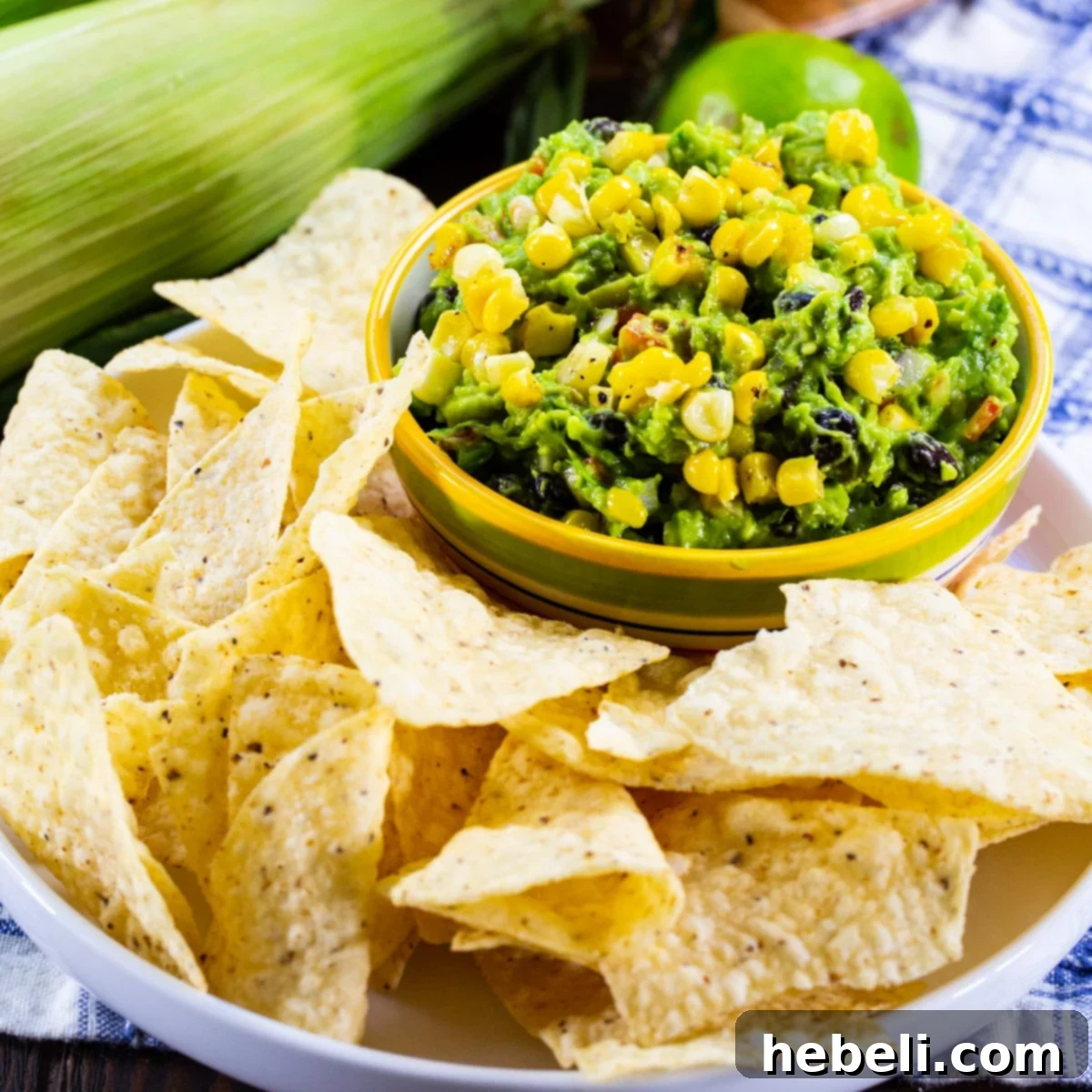 Creamy Black Bean and Corn Guacamole in a rustic bowl, surrounded by a generous spread of crispy tortilla chips, inviting a delicious dip.
