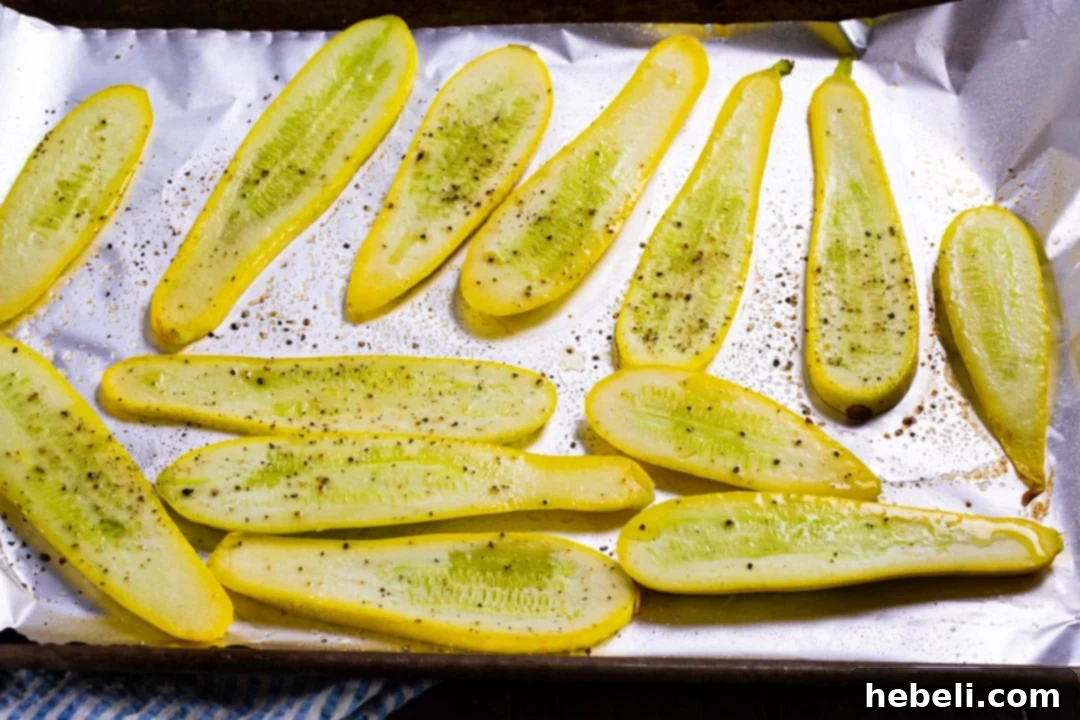 Crispy Panko Parmesan Squash Fries 3 Thinly sliced yellow squash pieces seasoned with salt and pepper, arranged on a baking sheet before initial baking.
