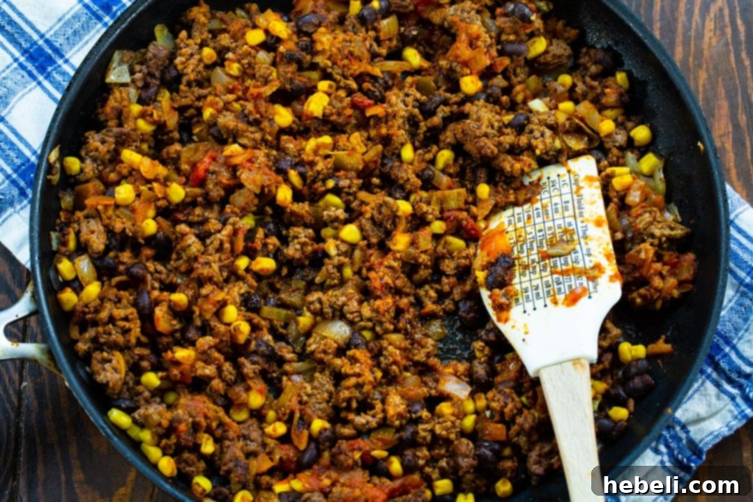 Close-up of the vibrant taco-seasoned ground beef, black beans, and corn filling simmering in a large nonstick skillet.