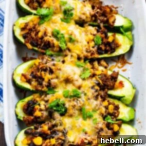 A close-up of a finished Taco Zucchini Boat, artfully garnished with fresh toppings on a plate.