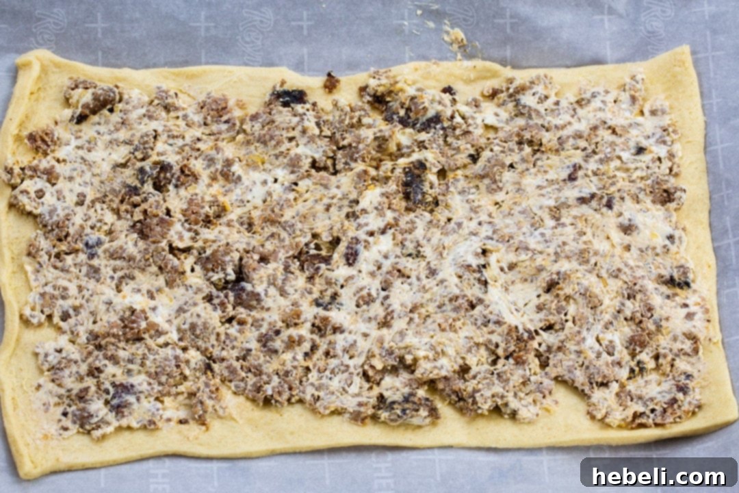 Close-up of the savory sausage and cream cheese mixture evenly spread onto a crescent dough sheet.