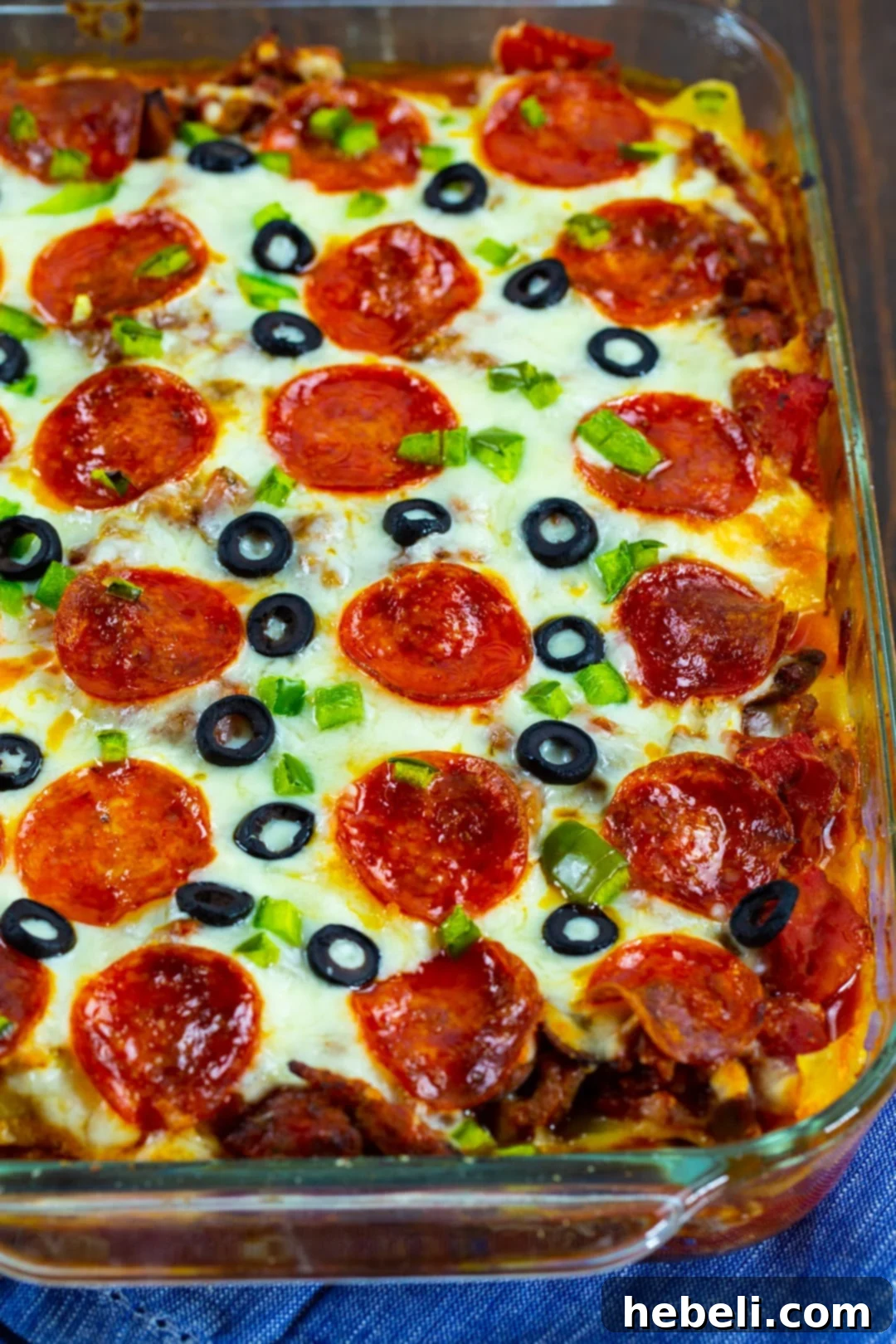 A large baking dish filled with freshly baked Pizza Lasagna, golden brown and bubbling with melted cheese, ready to be portioned and served.