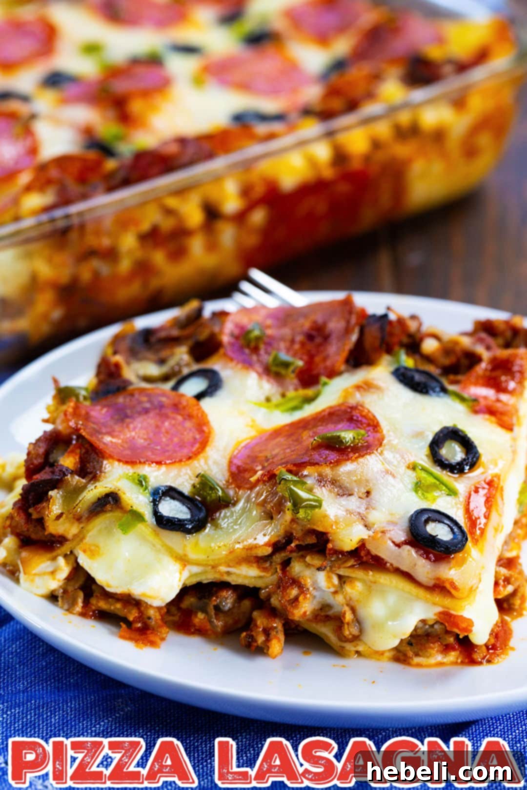 A close-up of a generous slice of Pizza Lasagna, revealing perfectly melted cheese, tender noodles, and a variety of colorful pizza toppings, served on a rustic plate.
