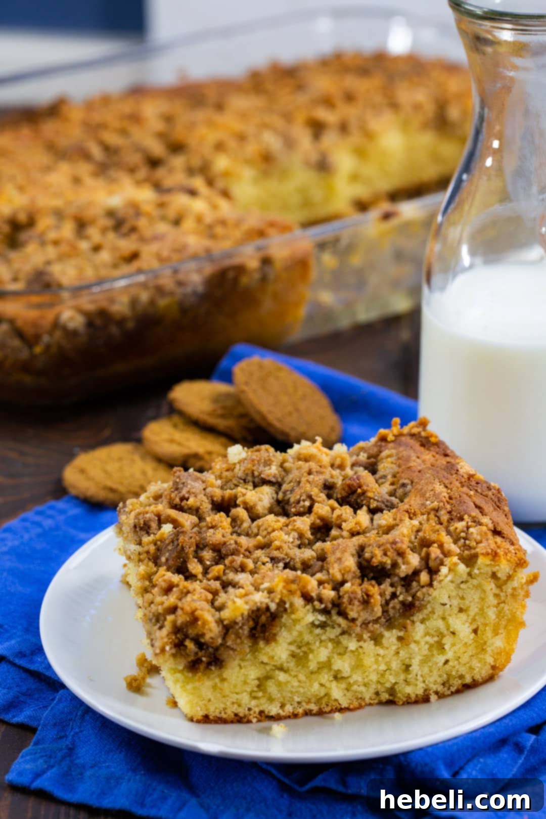 Close-up of a piece of Coffee Cake on a plate with the rest of the cake in the background, highlighting the tender crumb and slight texture variation from the batter.