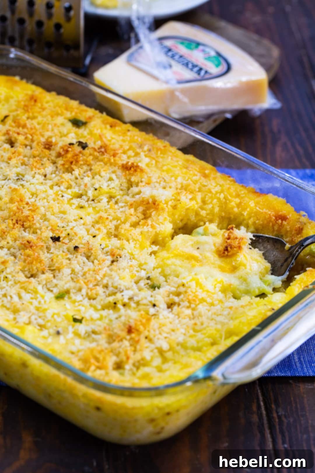 Creamy Cheesy Potato Bake 4 A spoon scooping a generous portion of Cheesy Mashed Potato Casserole from a dish, revealing its creamy interior.